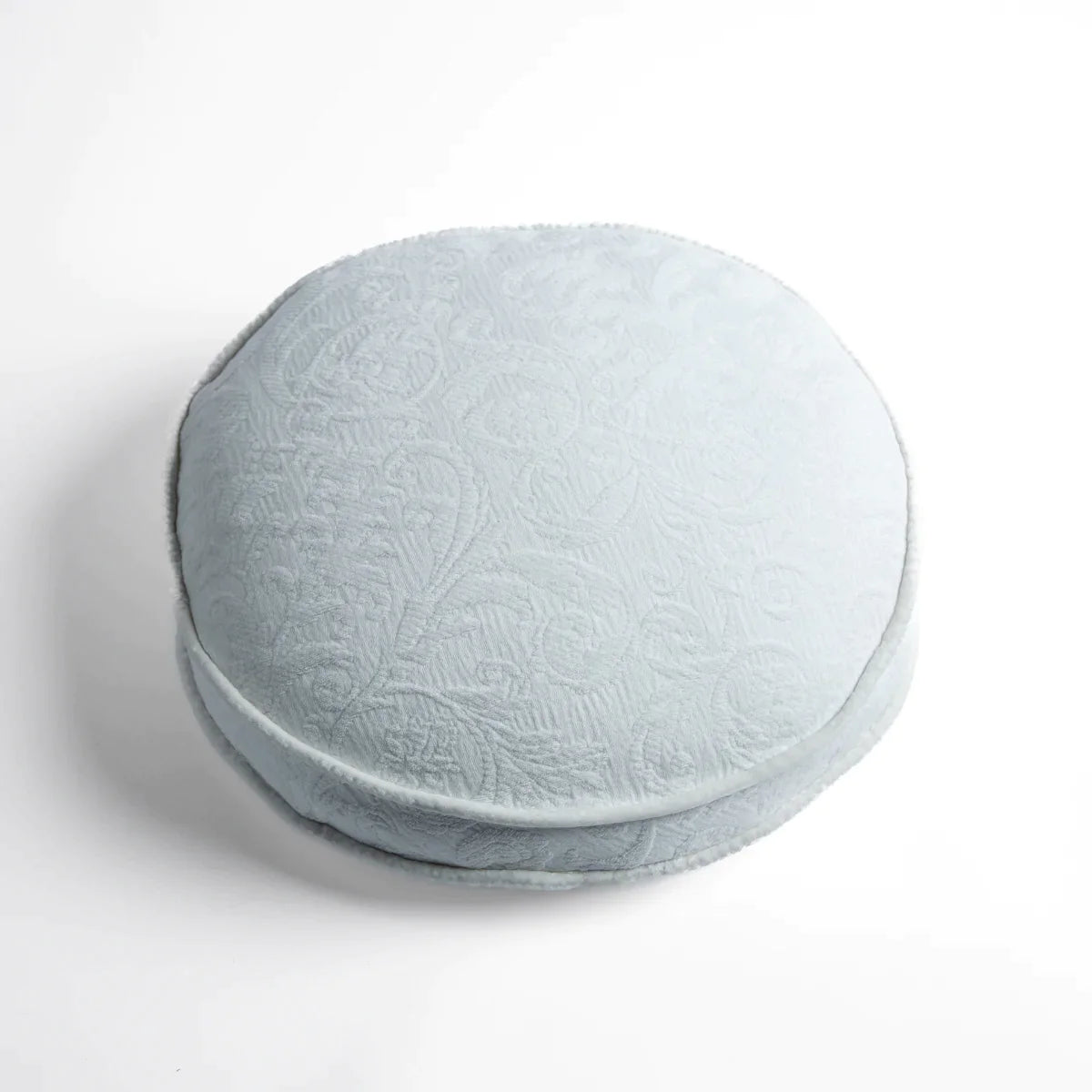Winter White: Organic cotton damask round pillow with silk velvet trim on white background β overhead angle.
