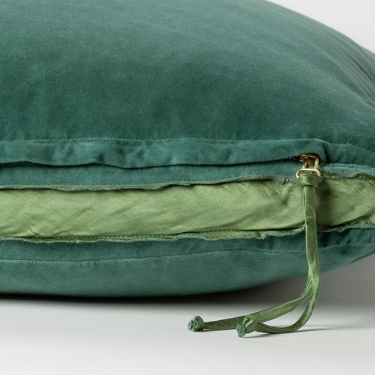 Jade: Close-up of charmeuse gusset, raw-edge trim, and brass zipper detail on Harlow pillow - side view.