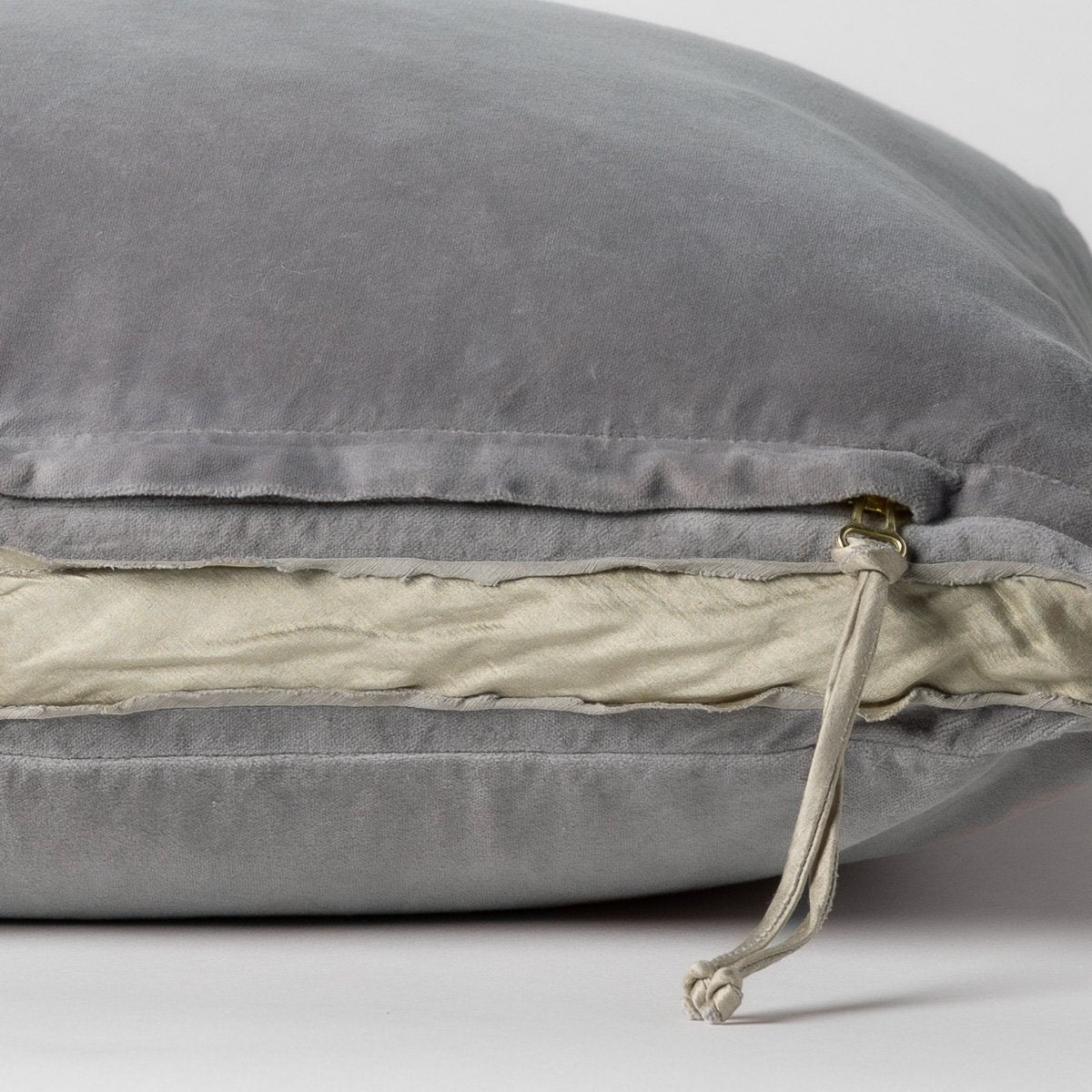 Moonlight: Close-up of charmeuse gusset, raw-edge trim, and brass zipper detail on Harlow pillow - side view.