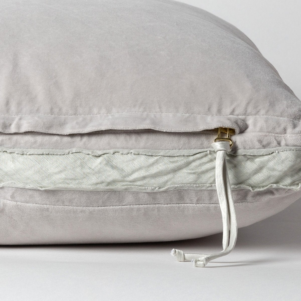 Sterling: Close-up of charmeuse gusset, raw-edge trim, and brass zipper detail on cotton velvet sham - side view.