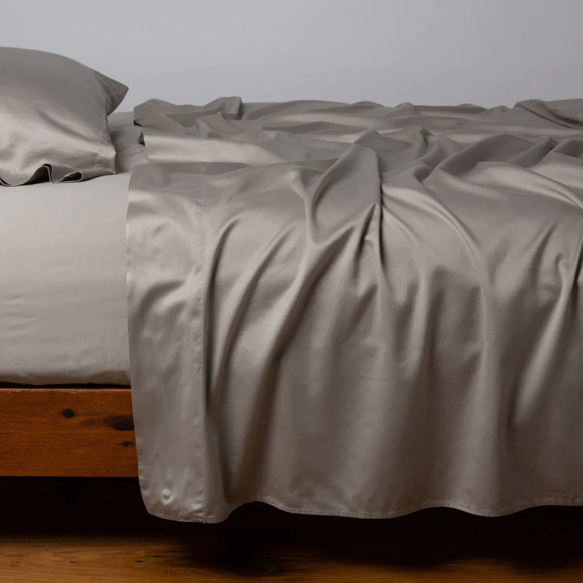Fog: Cotton sateen fitted sheet shown with matching flat sheet and sleeping pillow - side view.