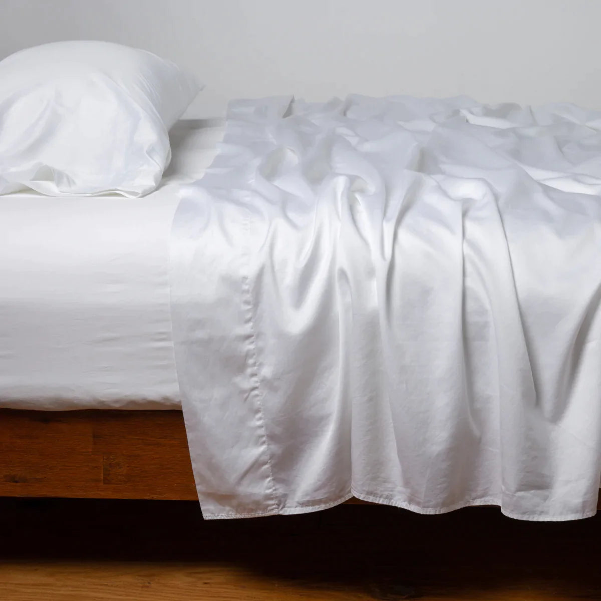 White: Cotton sateen fitted sheet shown with matching flat sheet and sleeping pillow - side view.