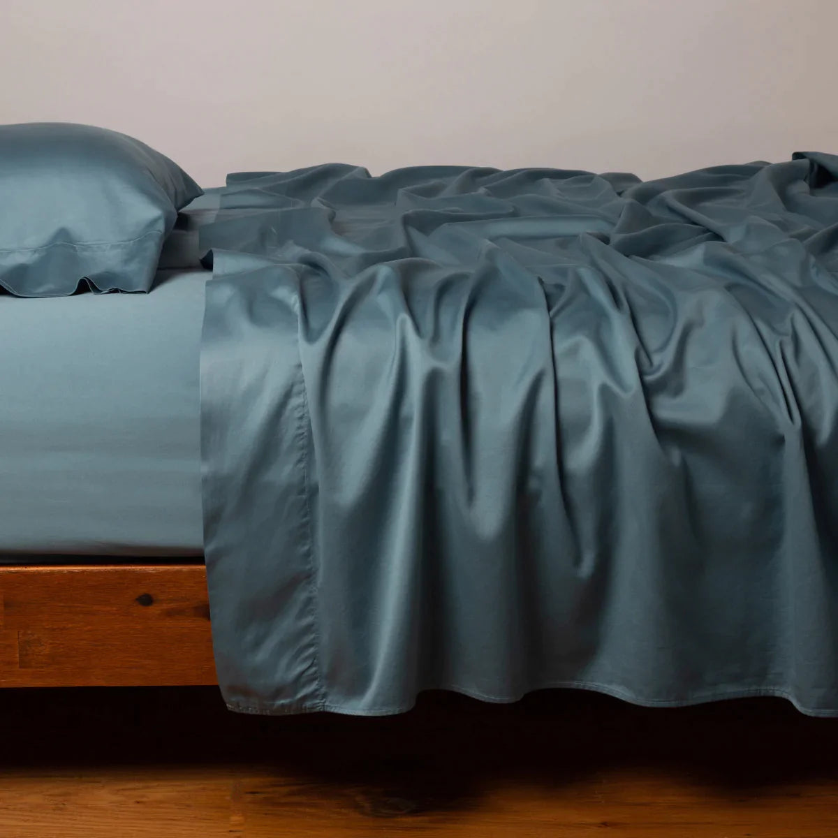 Cenote: Cotton sateen flat sheet, shown with matching fitted sheet and sleeping pillow - side view.