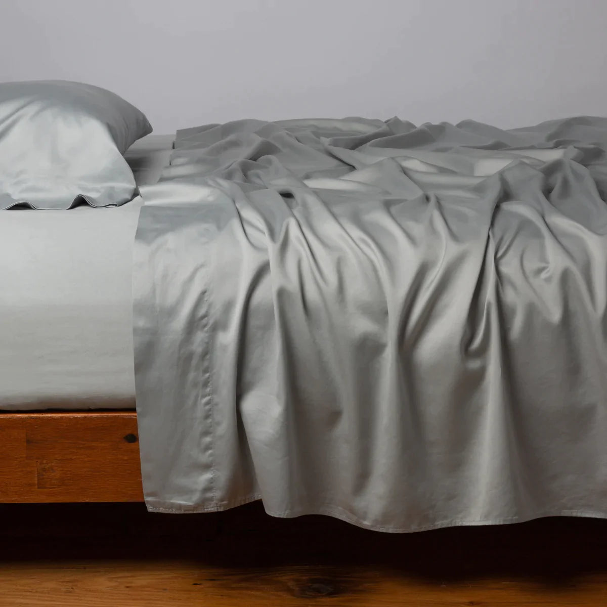 Mineral: Cotton sateen flat sheet, shown with matching fitted sheet and sleeping pillow - side view.