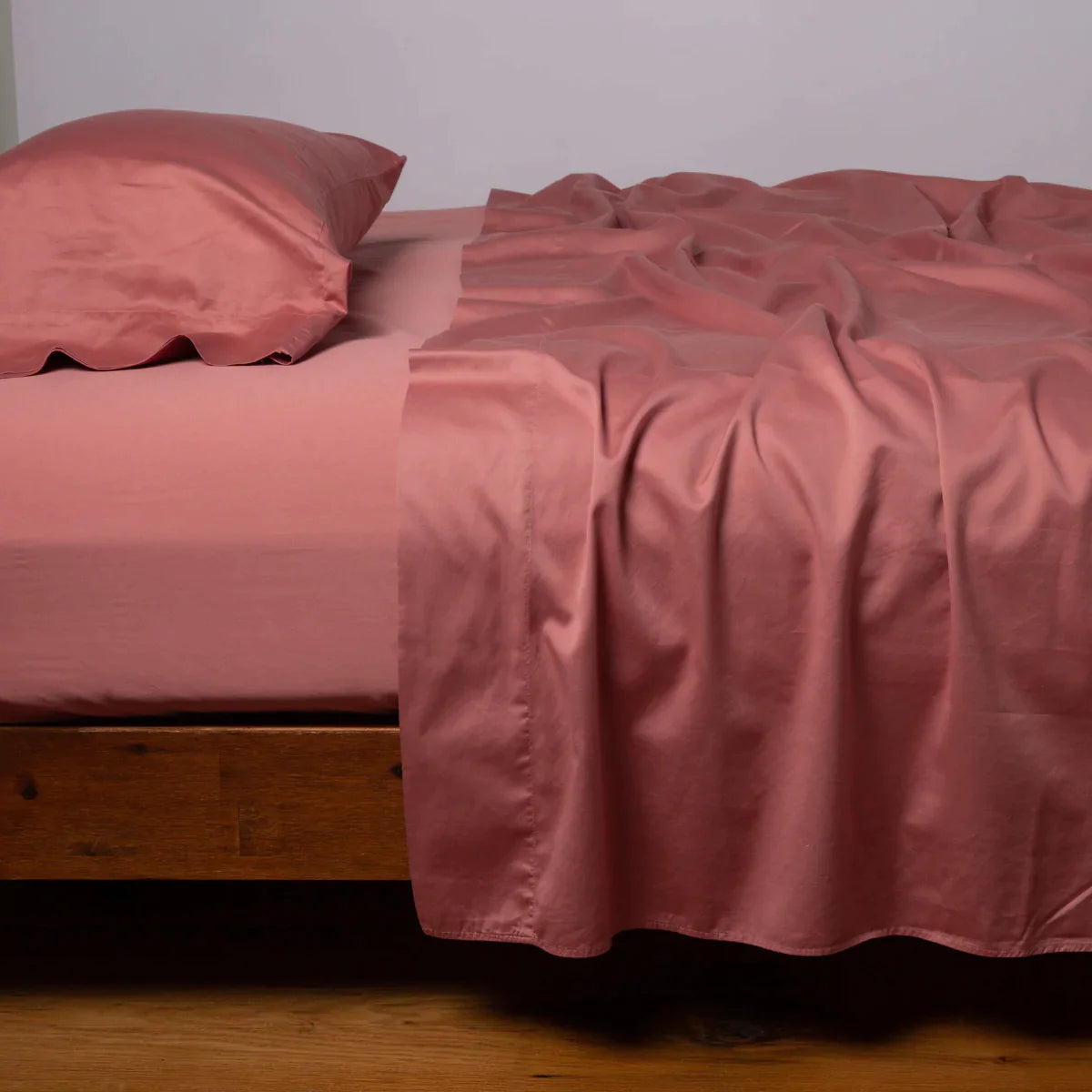 Poppy: Cotton sateen flat sheet, shown with matching fitted sheet and sleeping pillow - side view.