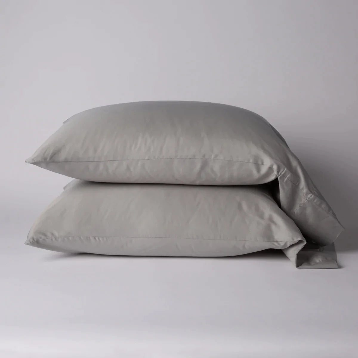 Fog: Two cotton sateen sleeping pillows, stacked neatly against a white backdrop - side view.