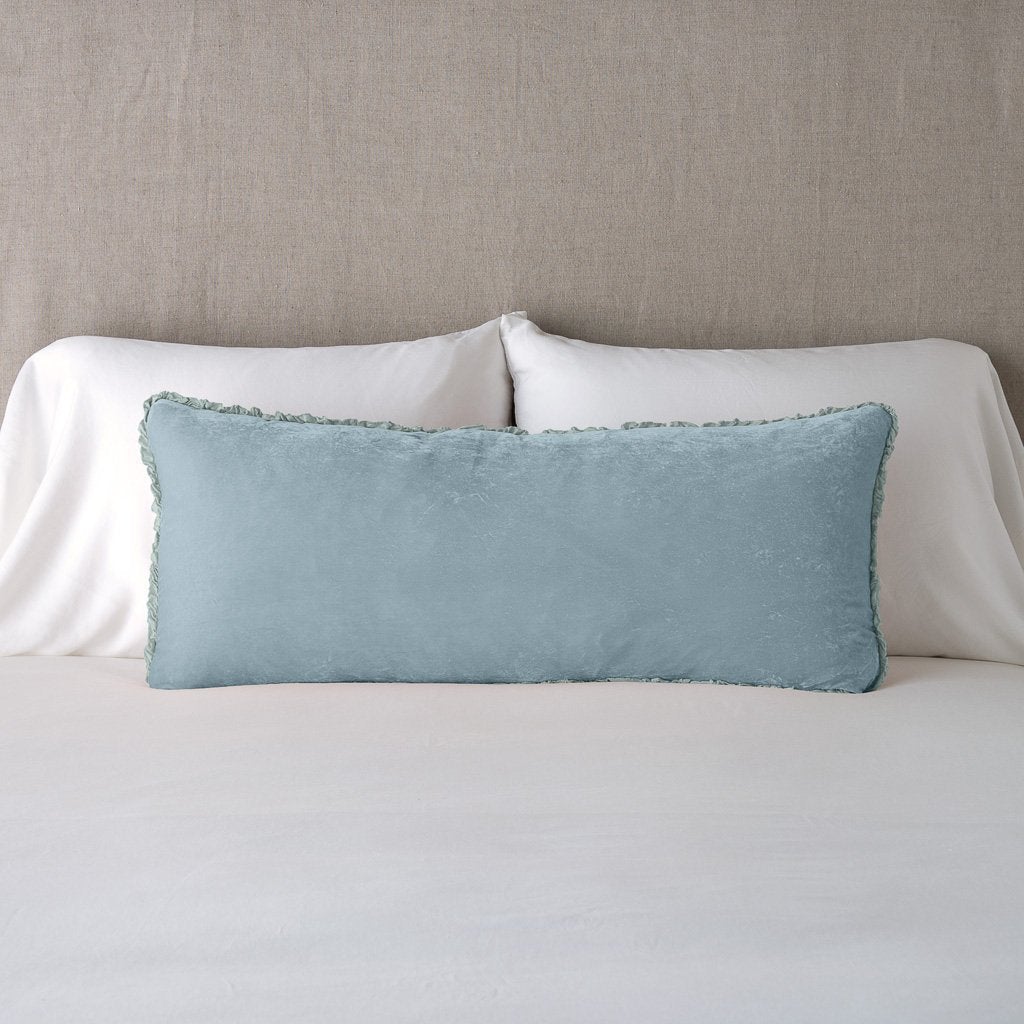 Cloud: Silk velvet lumbar pillow with petite ruffle, leaning upright against neutral bedding and headboard.