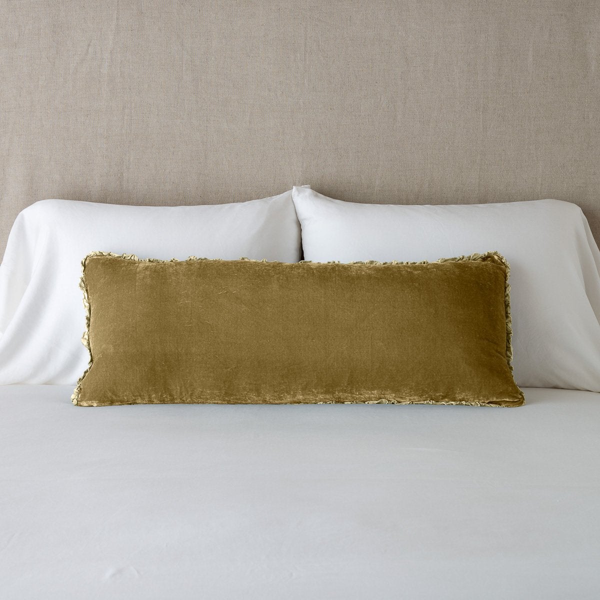 Honeycomb: Silk velvet lumbar pillow with petite ruffle, leaning upright against neutral bedding and headboard.