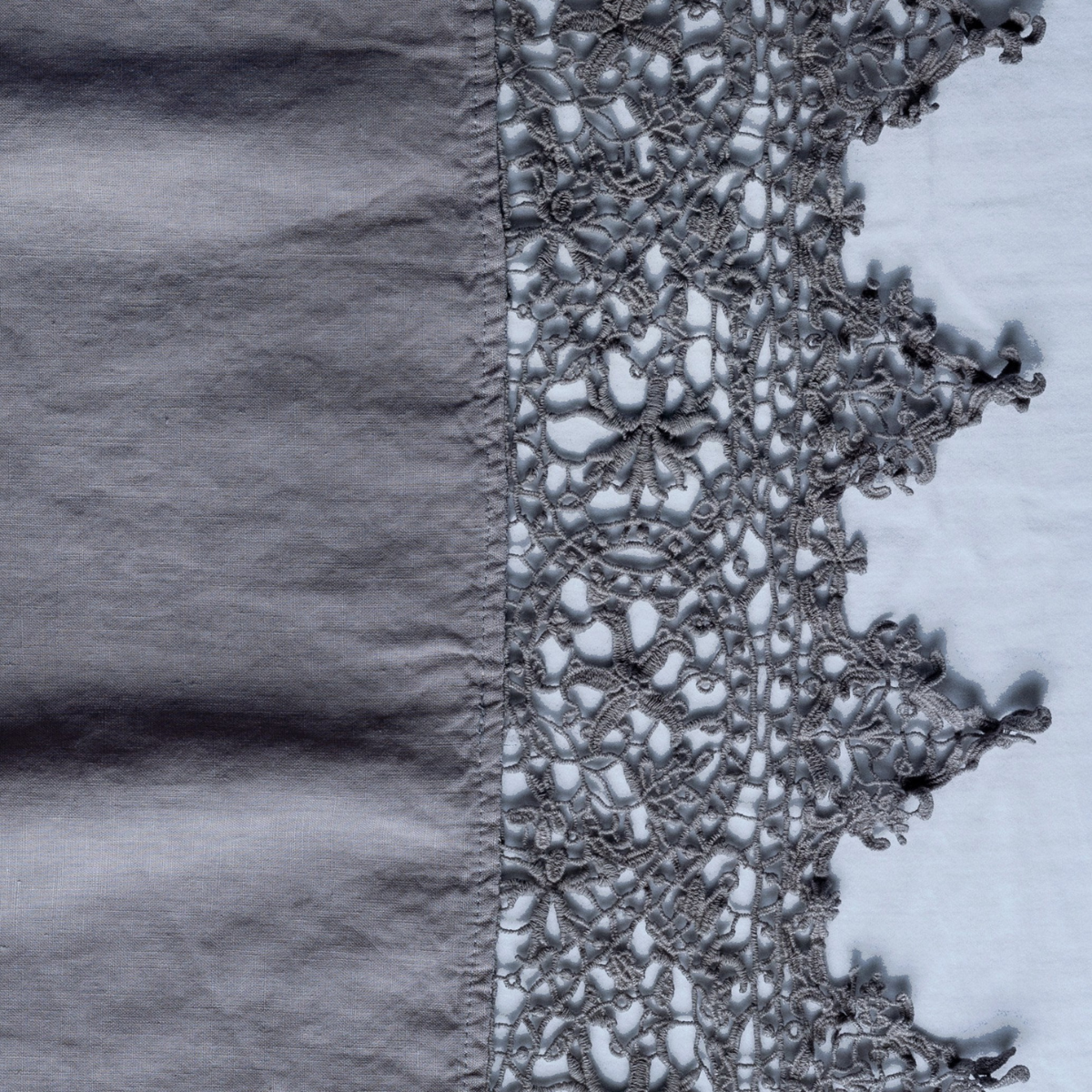 Moonlight: A close up of Frida, an antique cotton lace trim on a linen body, shown in moonlight, a saturated, cool, mid-dark grey tone.