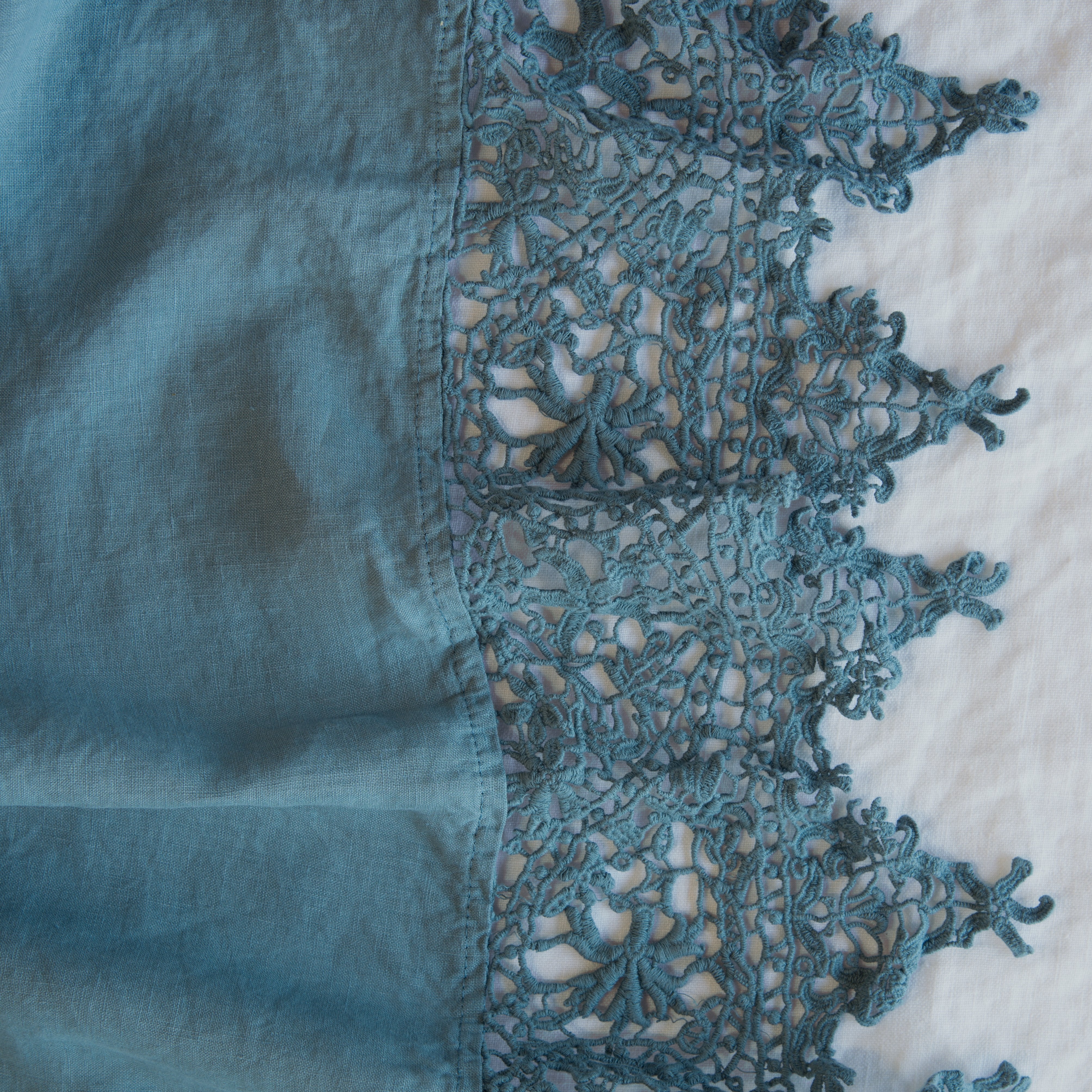 Cenote: A close up of Frida, an antique cotton lace trim on a linen body, shown in cenote, a vibrant, ocean-inspired blue-green.