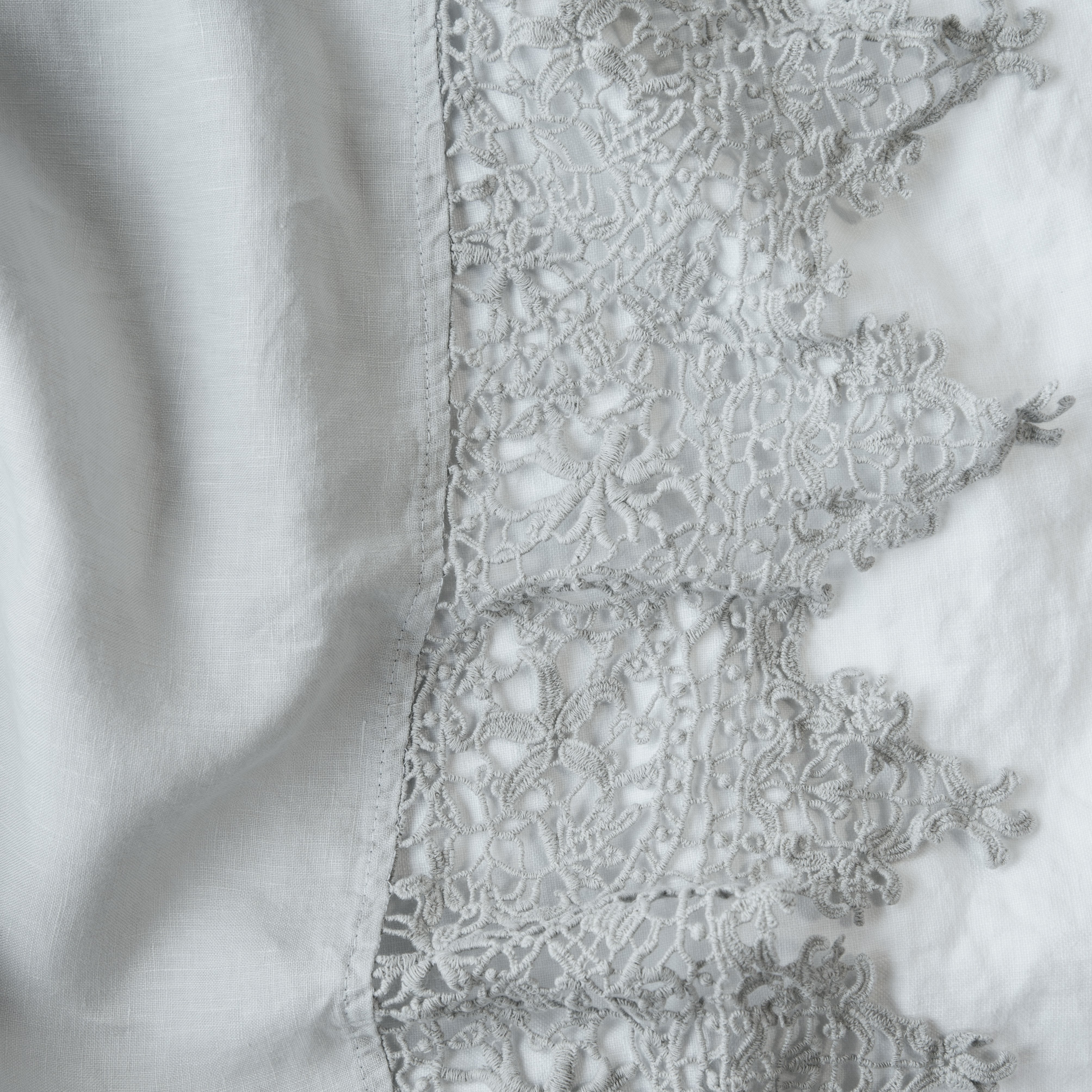 Cloud: A close up of Frida, an antique cotton lace trim on a linen body, shown in cloud, a soft, subtle sky blue-grey.