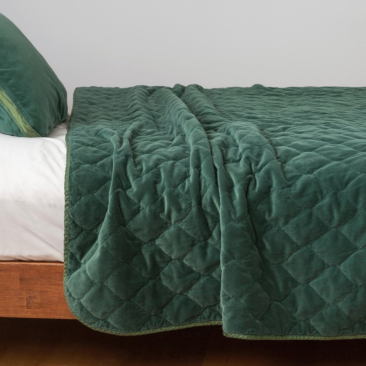 Jade: Quilted cotton velvet coverlet draped over a white fitted sheet - side view.