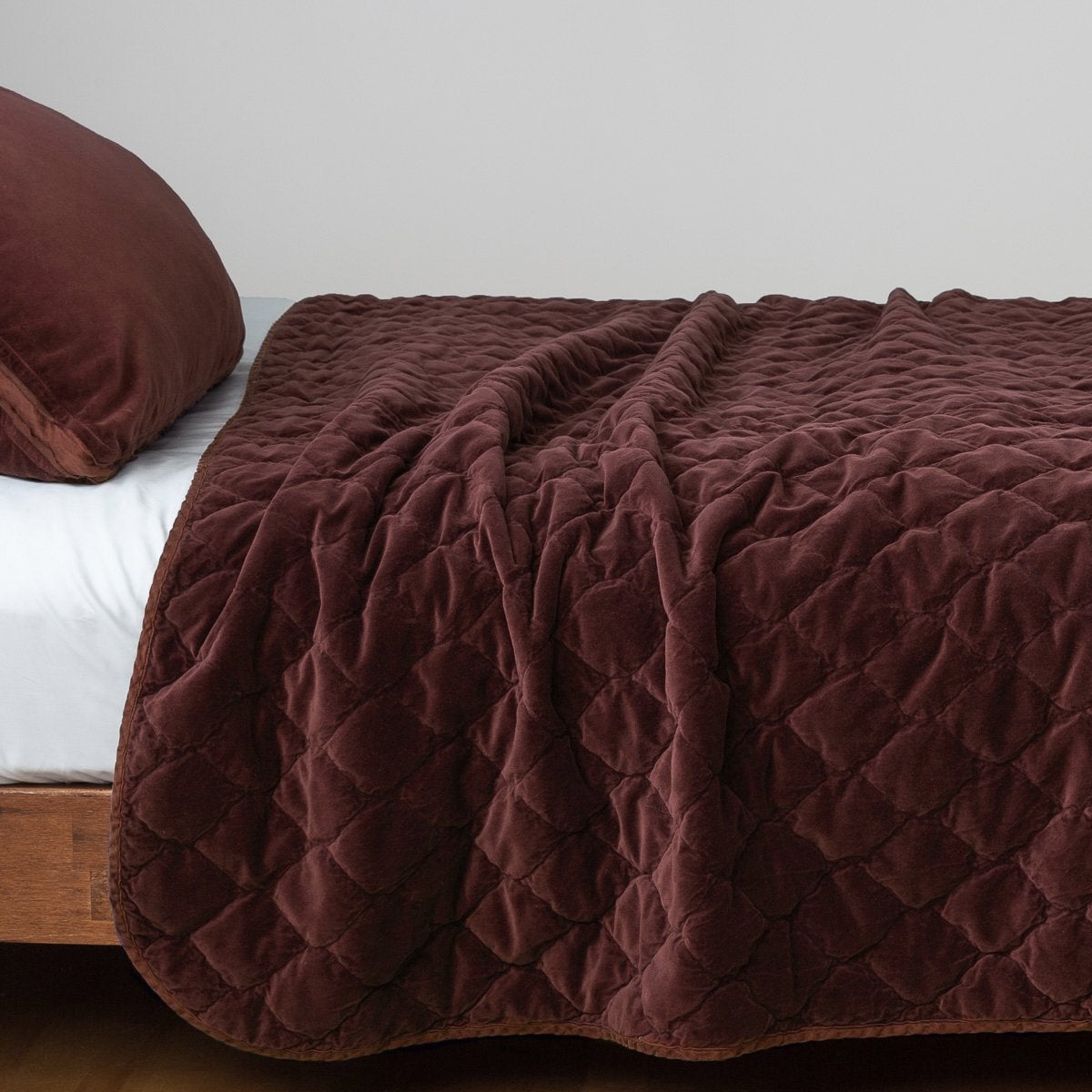 Mahogany: Quilted cotton velvet coverlet draped over a white fitted sheet - side view.