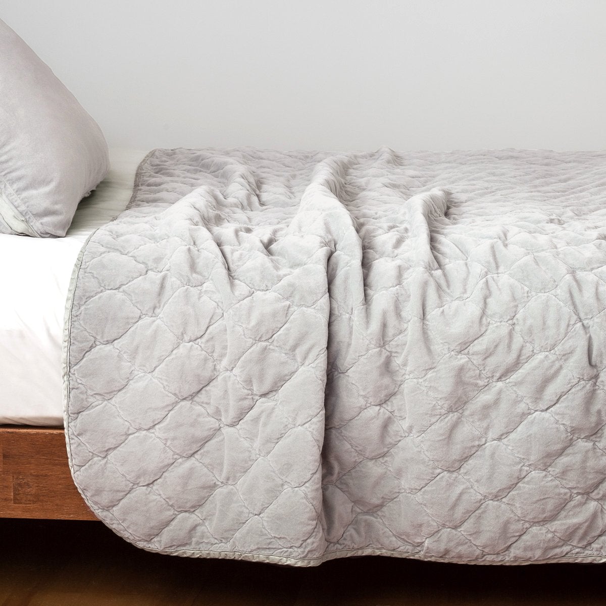 Sterling: Quilted cotton velvet coverlet draped over a white fitted sheet - side view.
