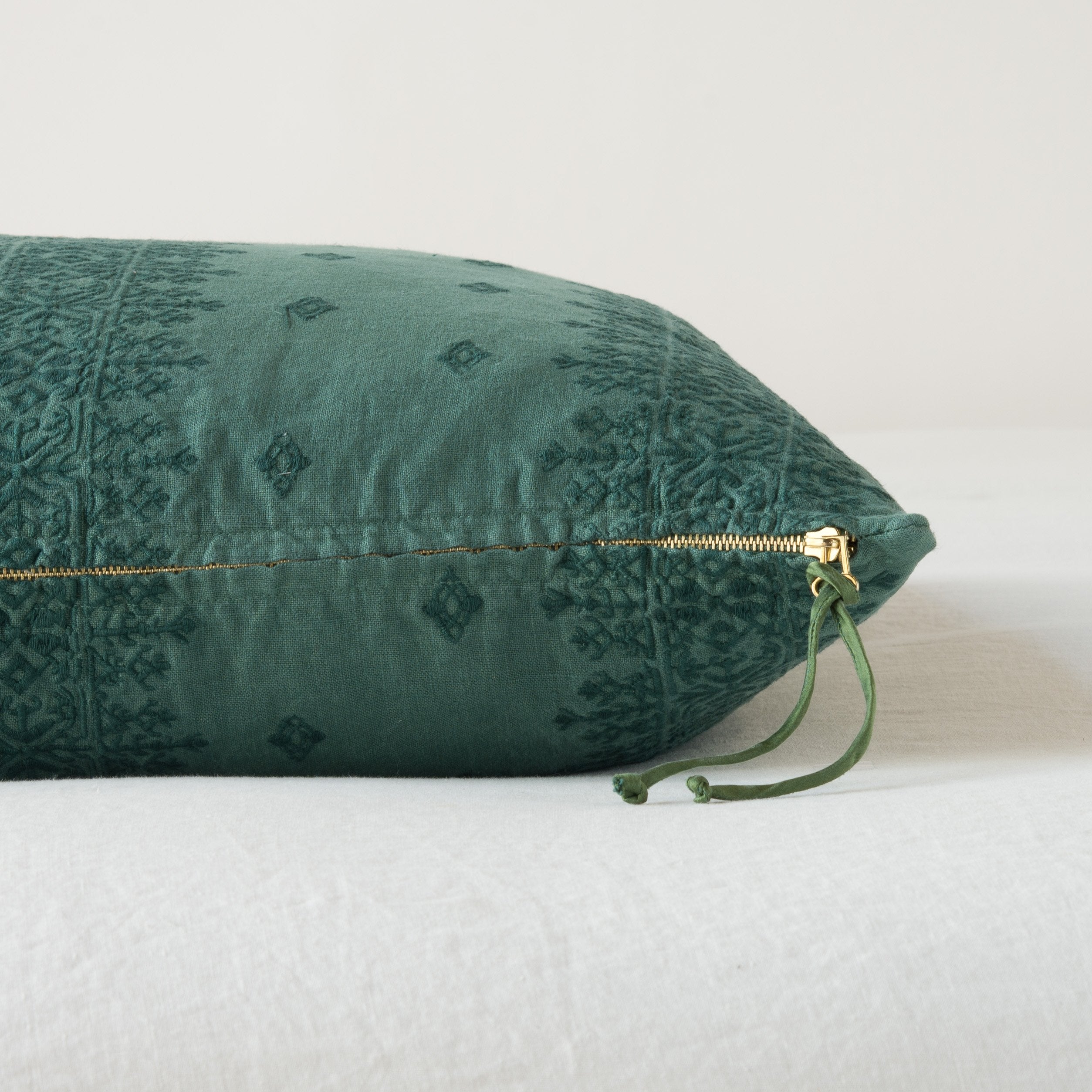 Jade: Close-up of brass zipper and charmeuse pull details on throw pillow - side view.