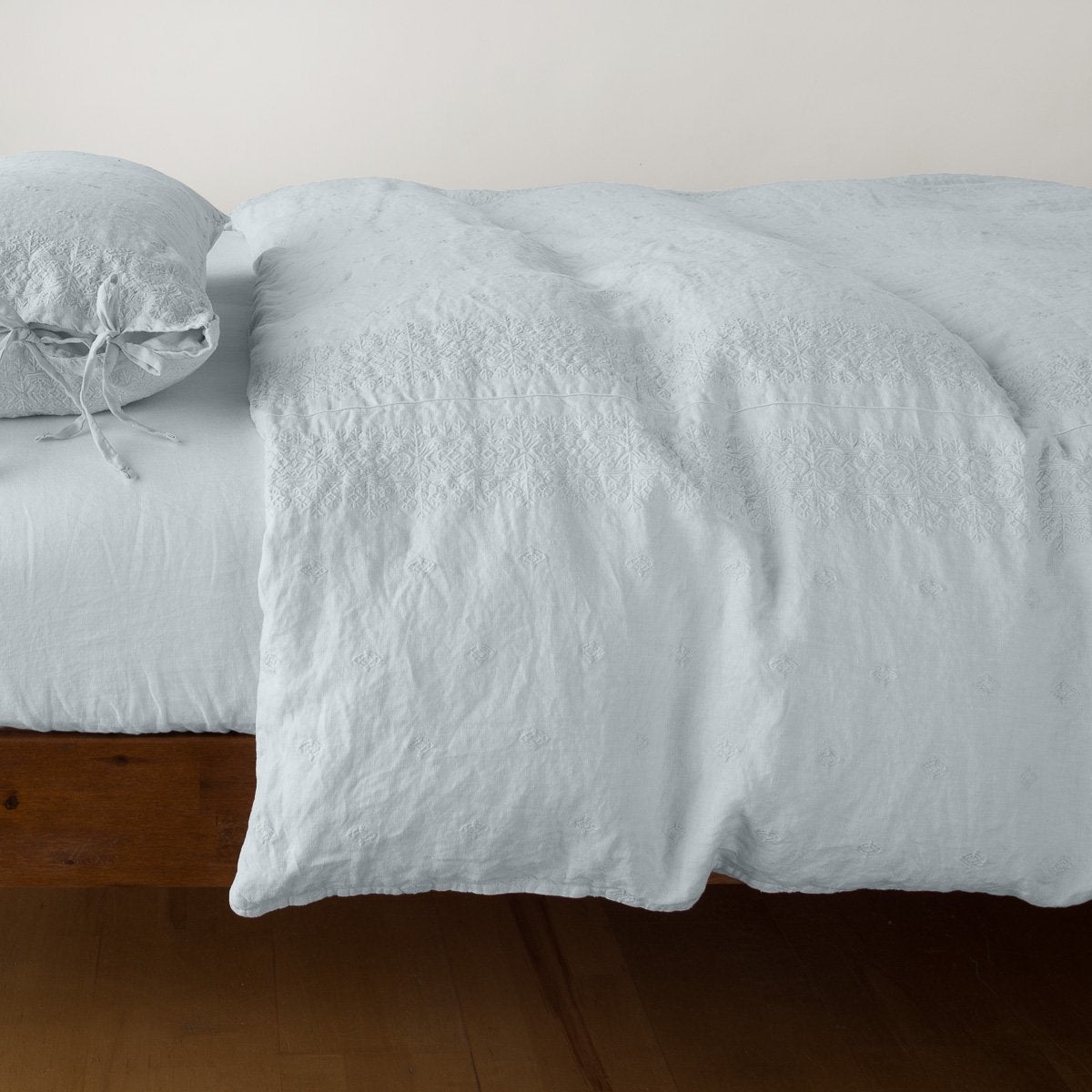 Cloud: lightly rumpled duvet cover on a monochromatic bed against a white background - side view.