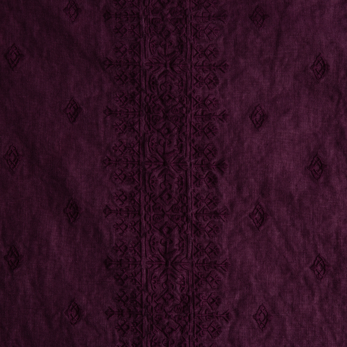 Fig: A close up of Ines, midweight linen with cotton embroidery, in fig, a richly saturated purple-garnet.