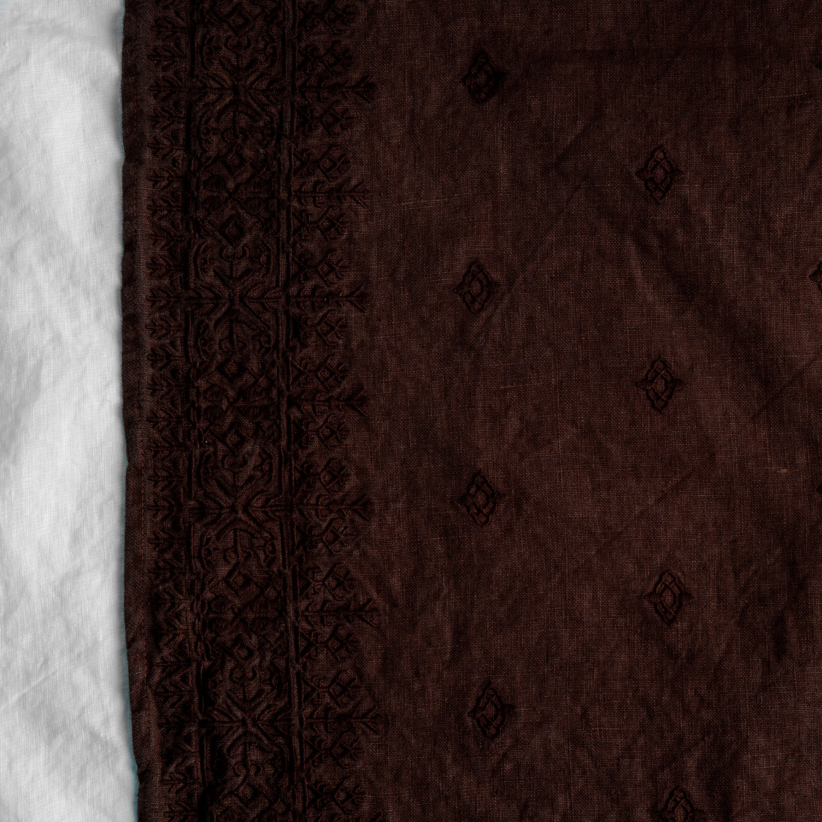 Mahogany: A close up of Ines, midweight linen with cotton embroidery, in mahogany, a deep, earthen, reddish brown.