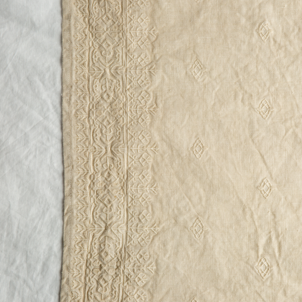 Parchment: A close up of Ines, midweight linen with cotton embroidery, in white.
