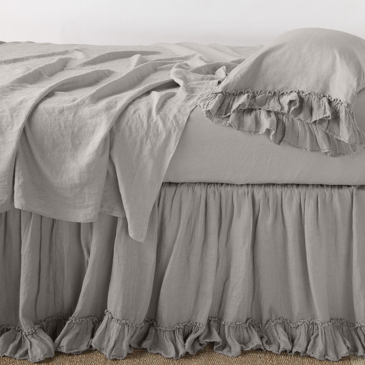 Fog: bed skirt layered with monochromatic linen sheeting - side view.