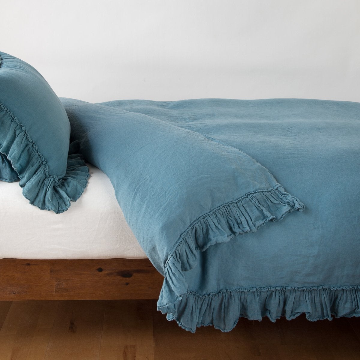 Cenote: duvet cover folded back over a white fitted sheet, shown with matching sham against a plain background - side view.