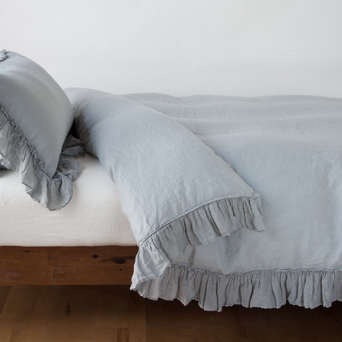 Mineral: duvet cover folded back over a white fitted sheet, shown with matching sham against a plain background - side view.