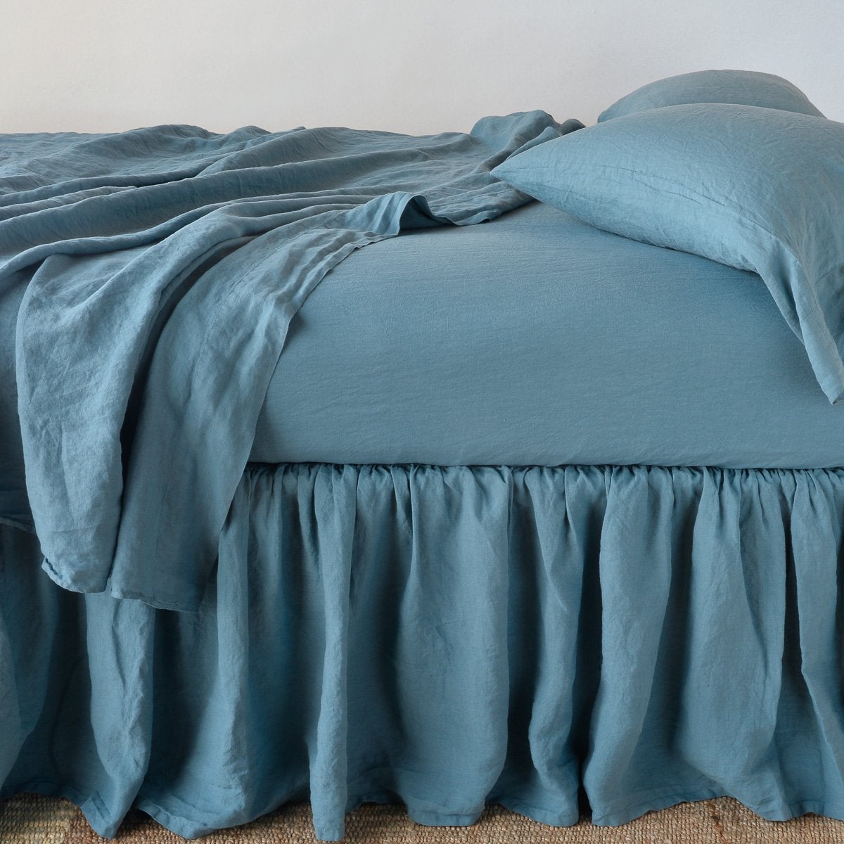 Cenote: bed skirt with matching rumpled sheets and sleeping pillows - side view.