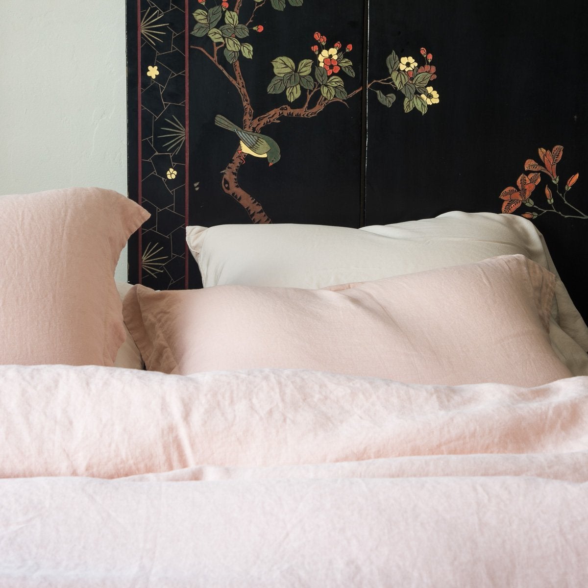 : Linen duvet cover and shams in soft pearl pink with dramatic dark floral wall panel - cropped head-on view.