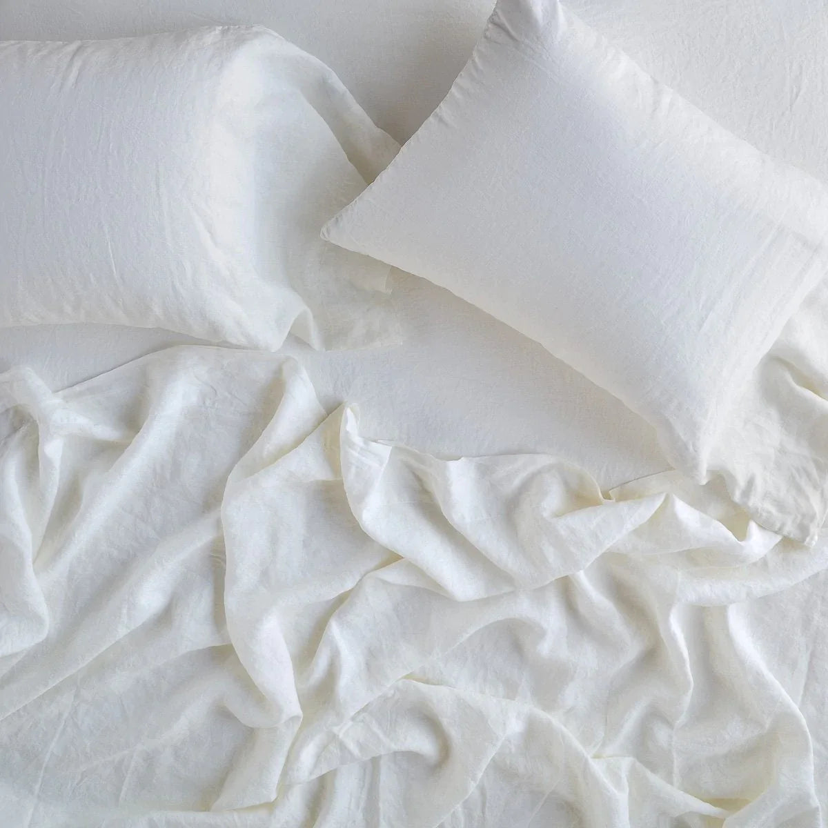 Winter White: fitted sheet with matching rumpled flat sheet and sleeping pillows - overhead view.
