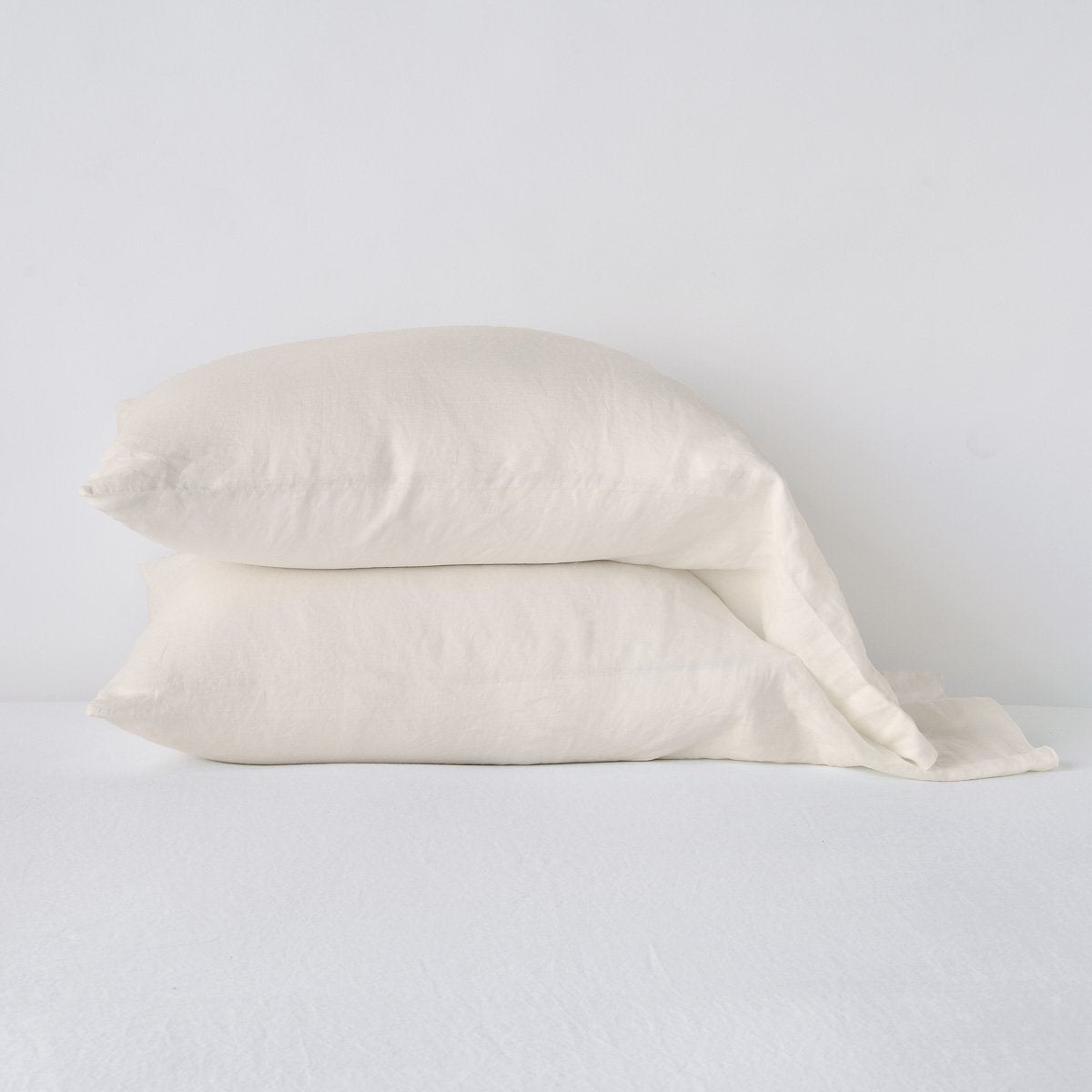 Parchment: Two sleeping pillows neatly stacked against a white background - side view.