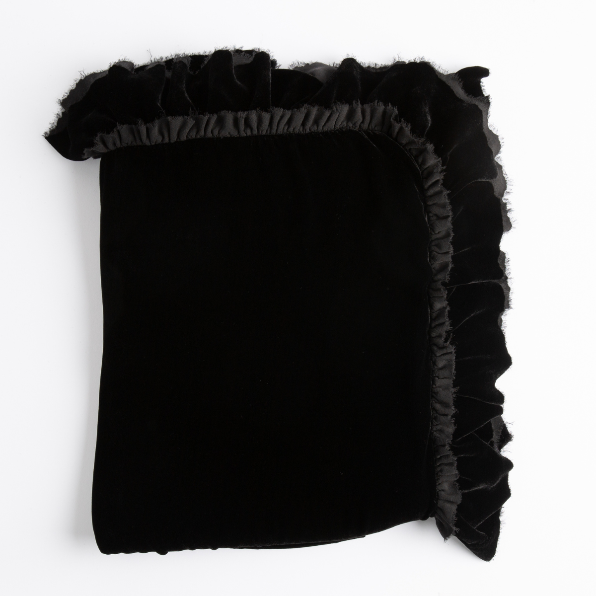 Corvino: folded blanket shows raw edge ruffle detail. - overhead on white background.
