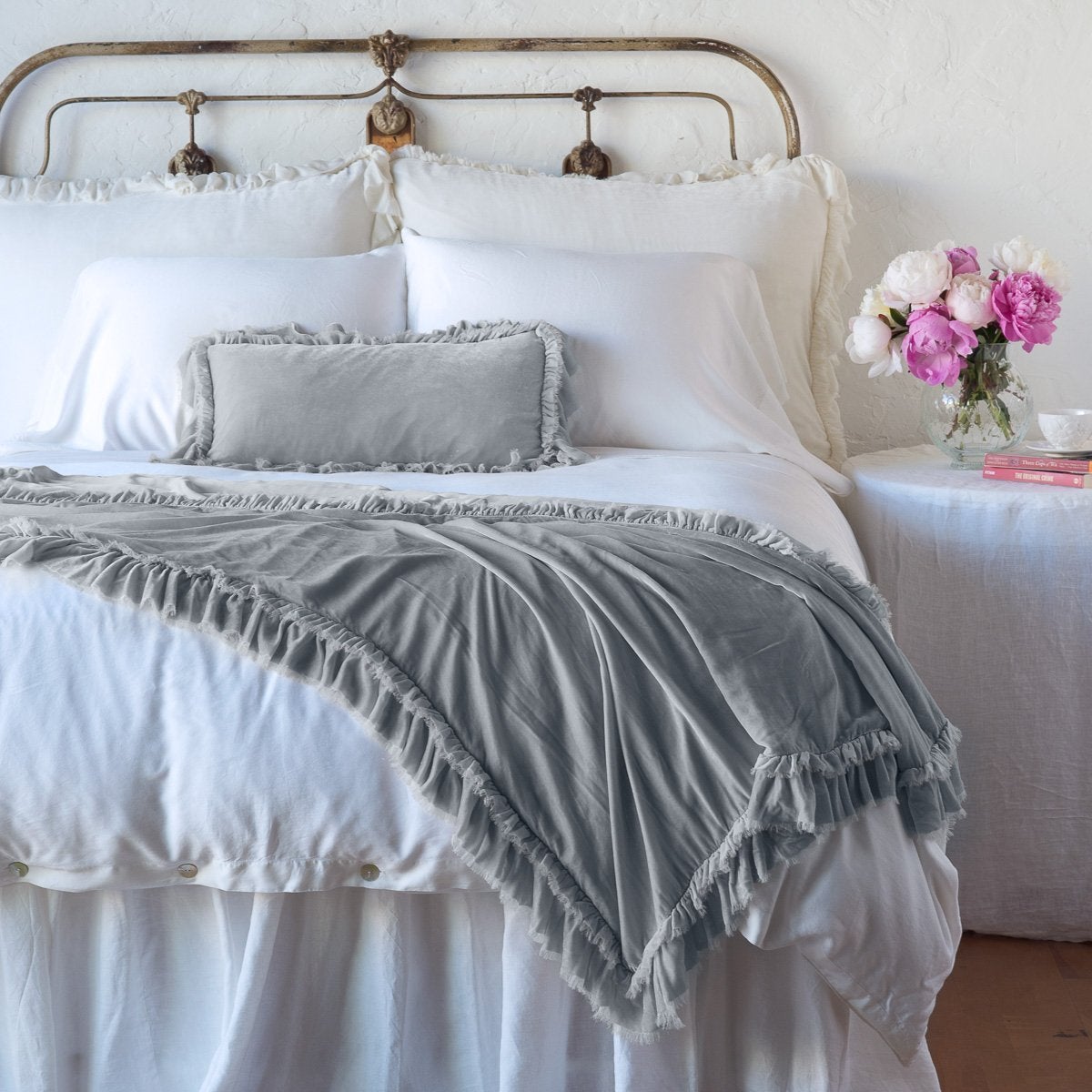 Sterling: throw blanket draped over the end of a white bed, shown with matching accent pillow - end of bed view.