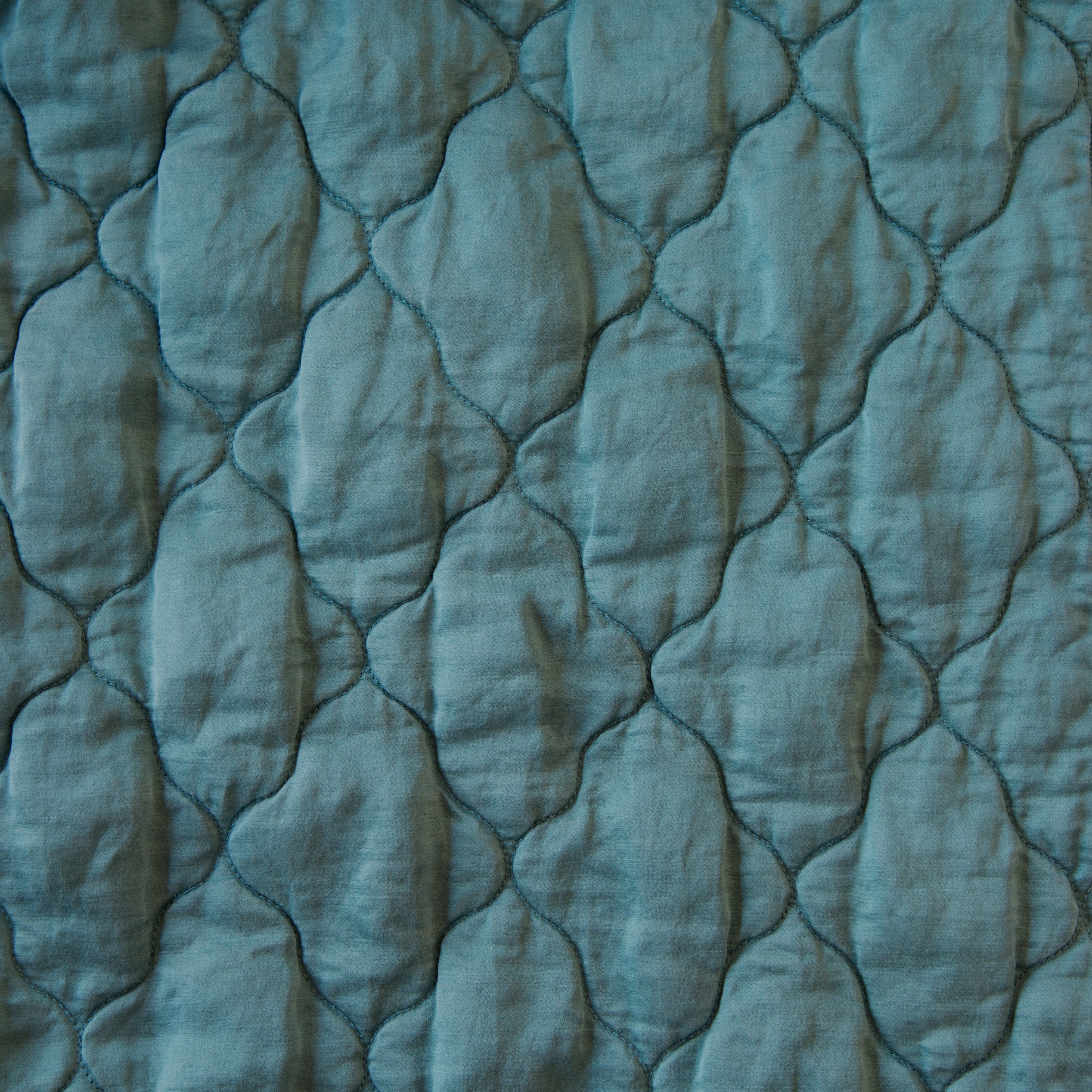 Cenote: Close-up of Luna silk charmeuse quilting in cenote, a vibrant, ocean-inspired blue-green.