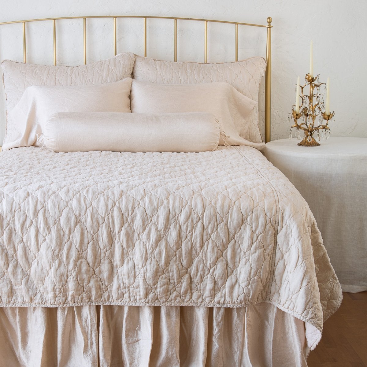 Pearl: shams on a shining, monochromatic bed with matching coverlet - end of bed view.