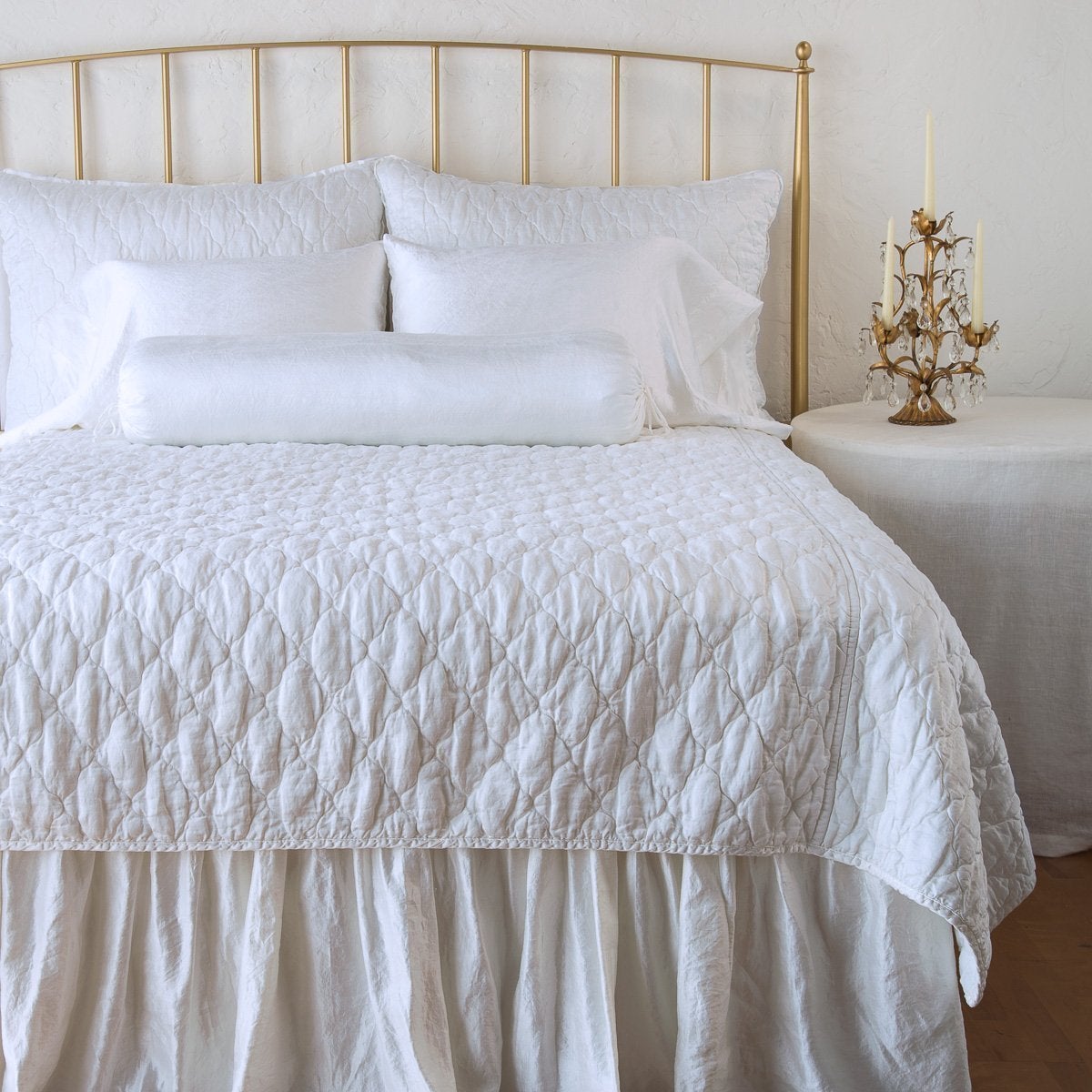 : Luna shams on a shining, monochromatic bed with matching coverlet, and charmeuse pillows and bed skirt - white, end of bed view.
