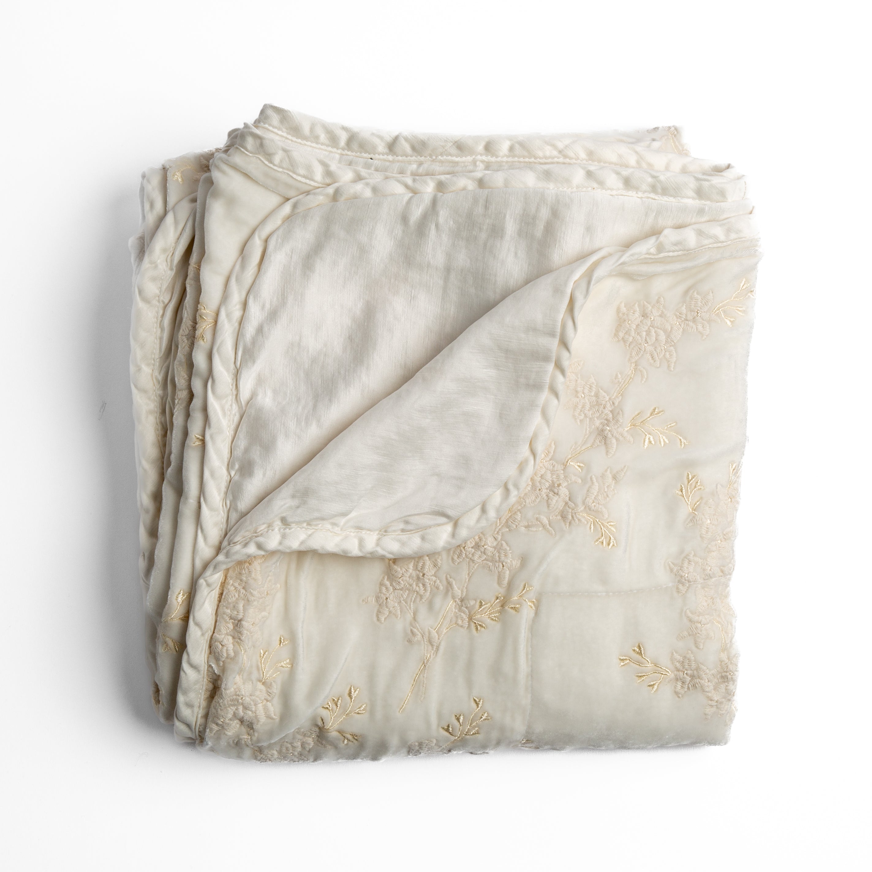 Winter White: overhead angle of the folded blanket with a corner pulled back to show the reverse and trim.