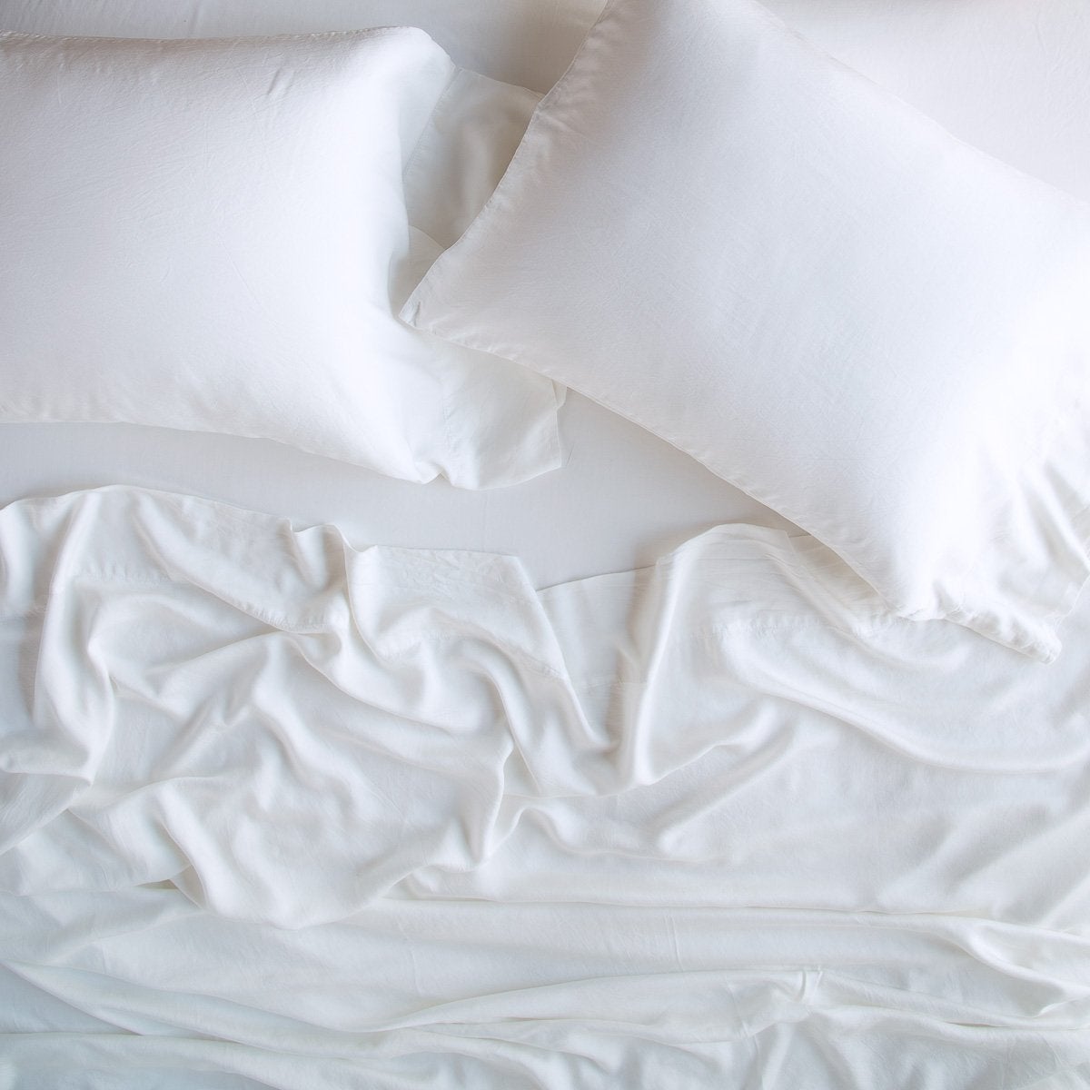 White: Rumpled sheeting, shown with matching sleeping pillows - overhead view.
