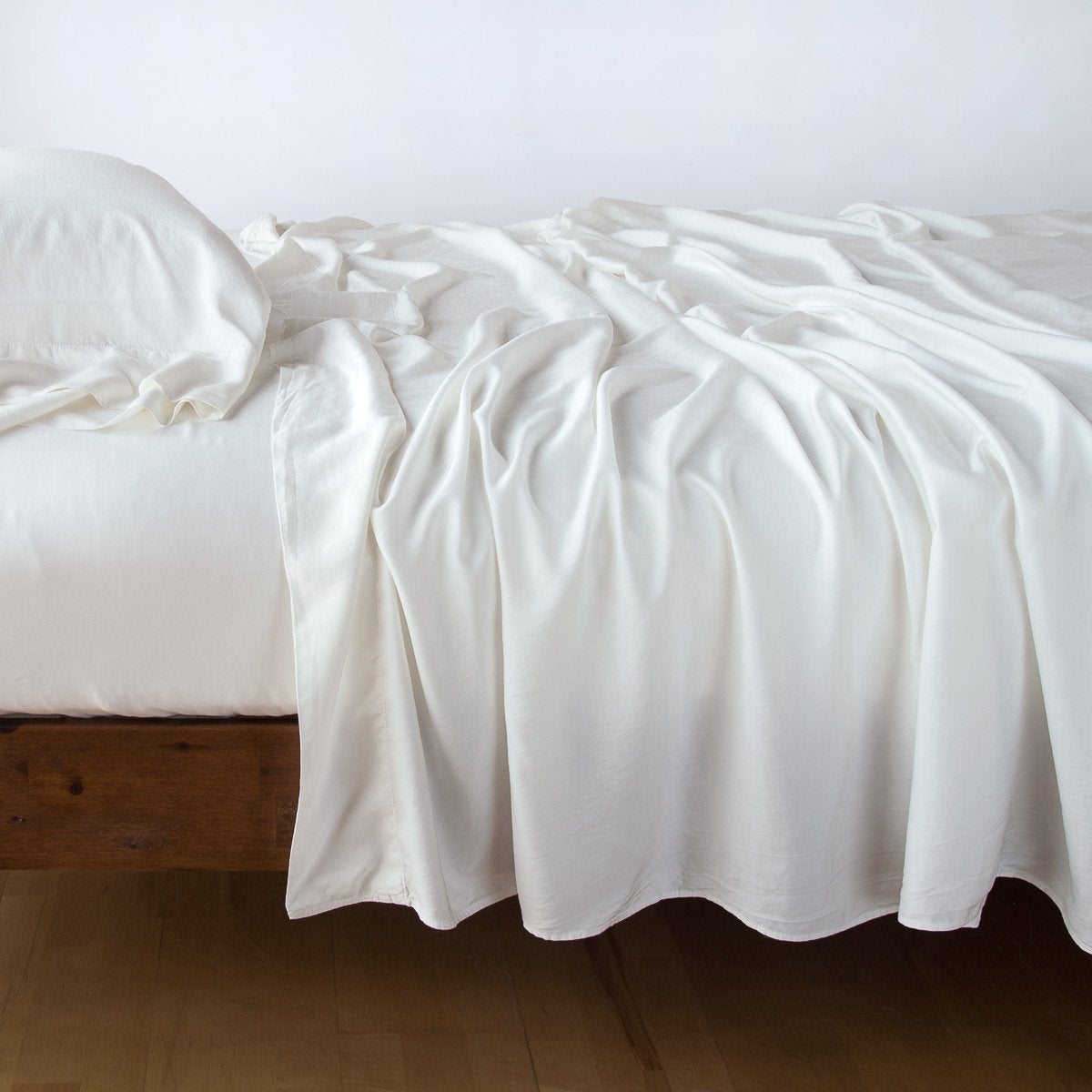 Winter White: Rumpled flat sheet with matching fitted sheet and sleeping pillow - side view.