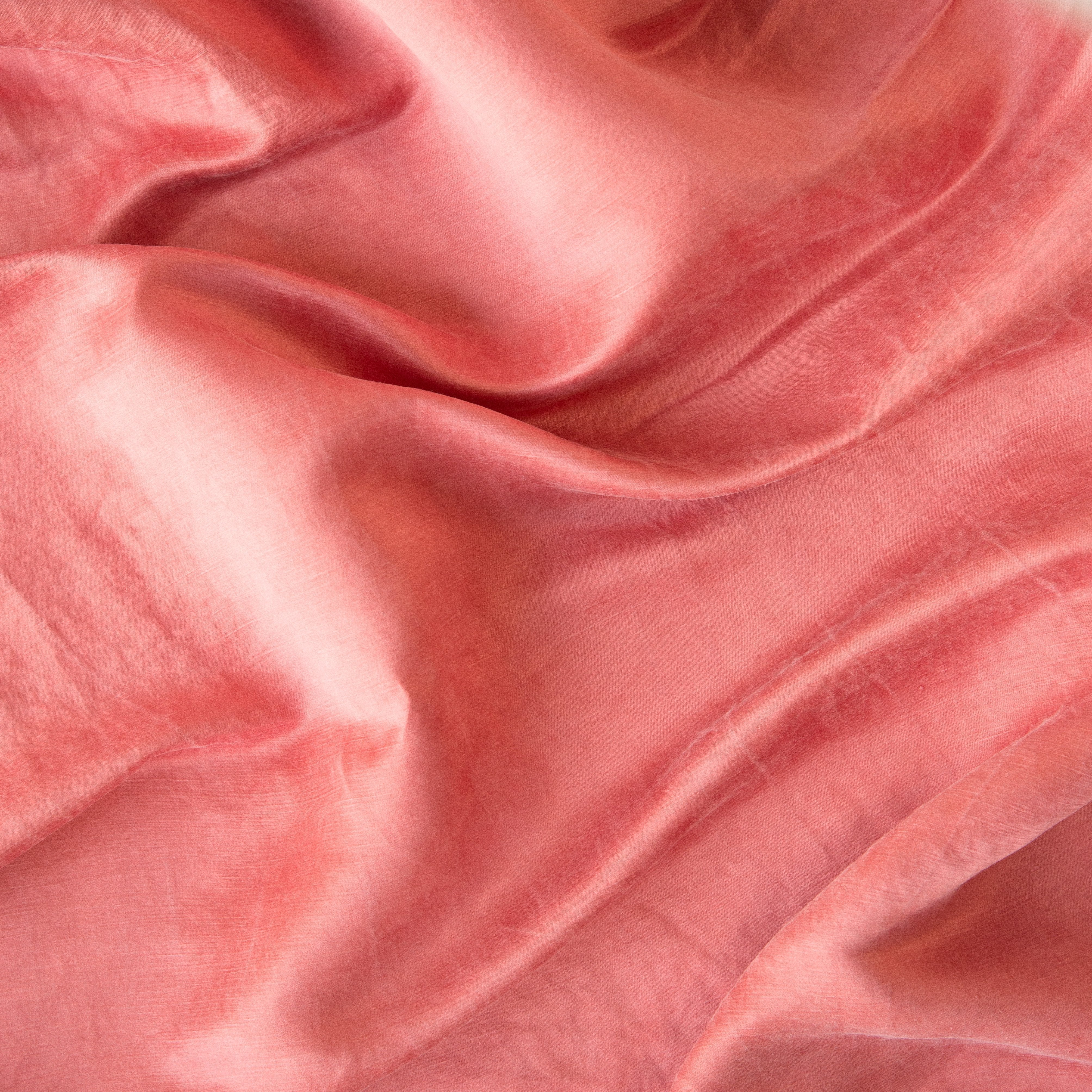 Poppy: Close-up of silk charmeuse in poppy, a warm coral pink.