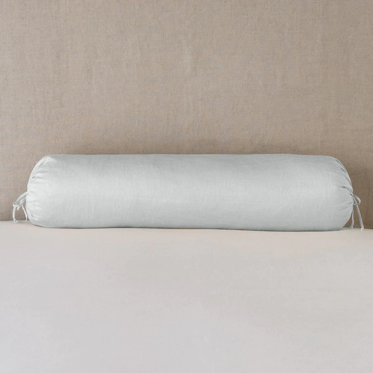 Cloud: bolster on white sheets with a neutral headboard.