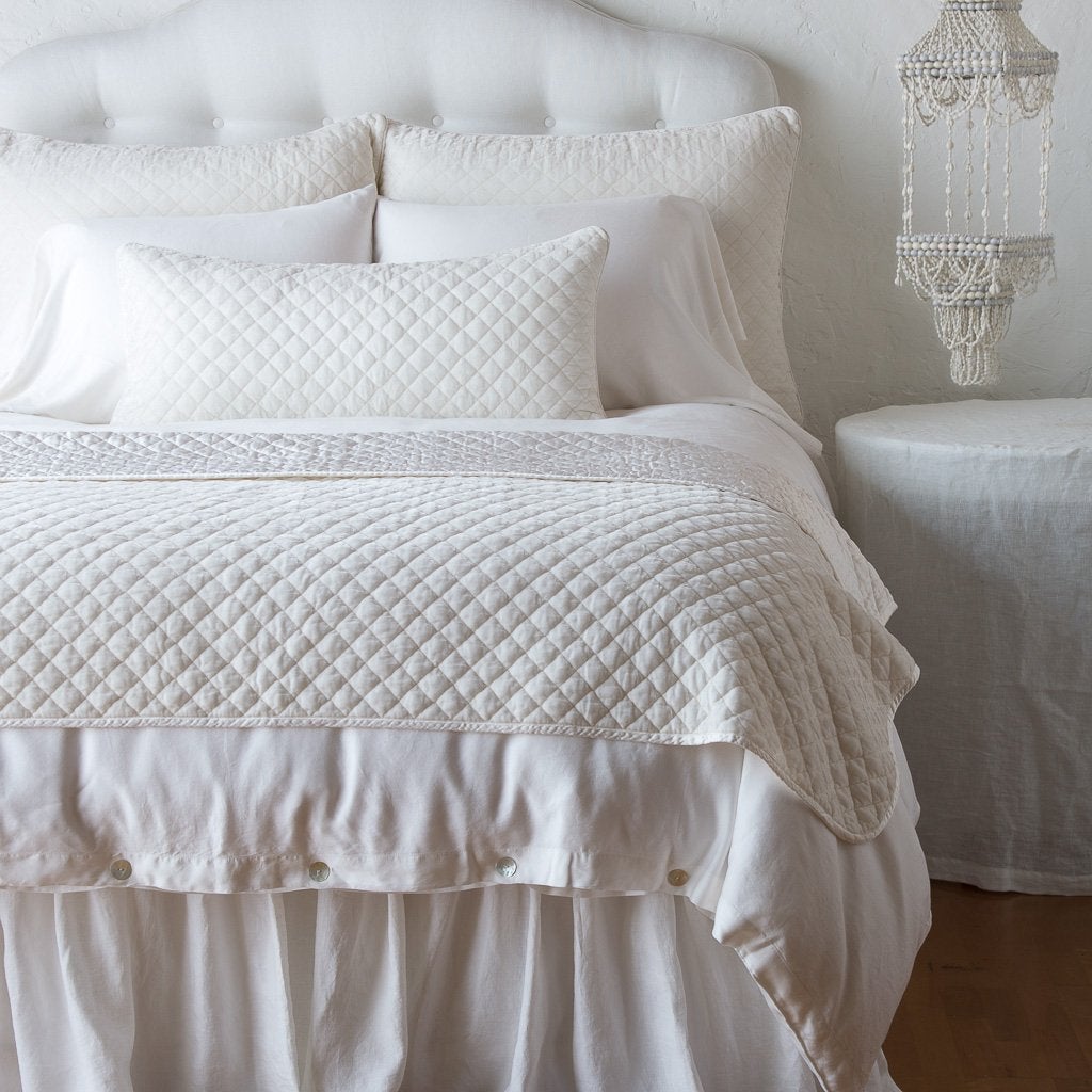 Winter White: 16x36 pillow and matching throw blanket on a white, neatly made bed - end of bed view.