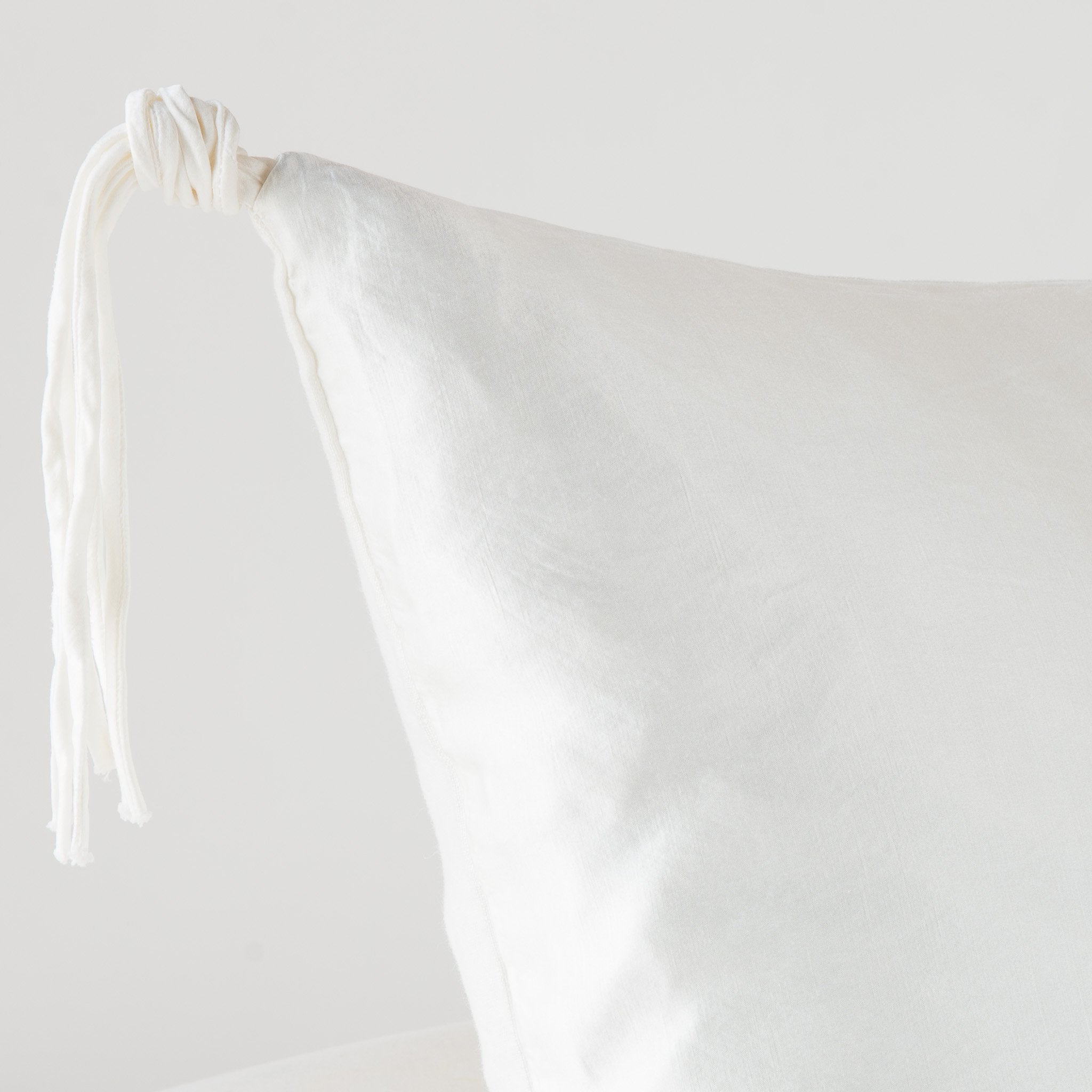 Winter White: Corner detail close-up, highlighting hand-tied charmeuse tassel.
