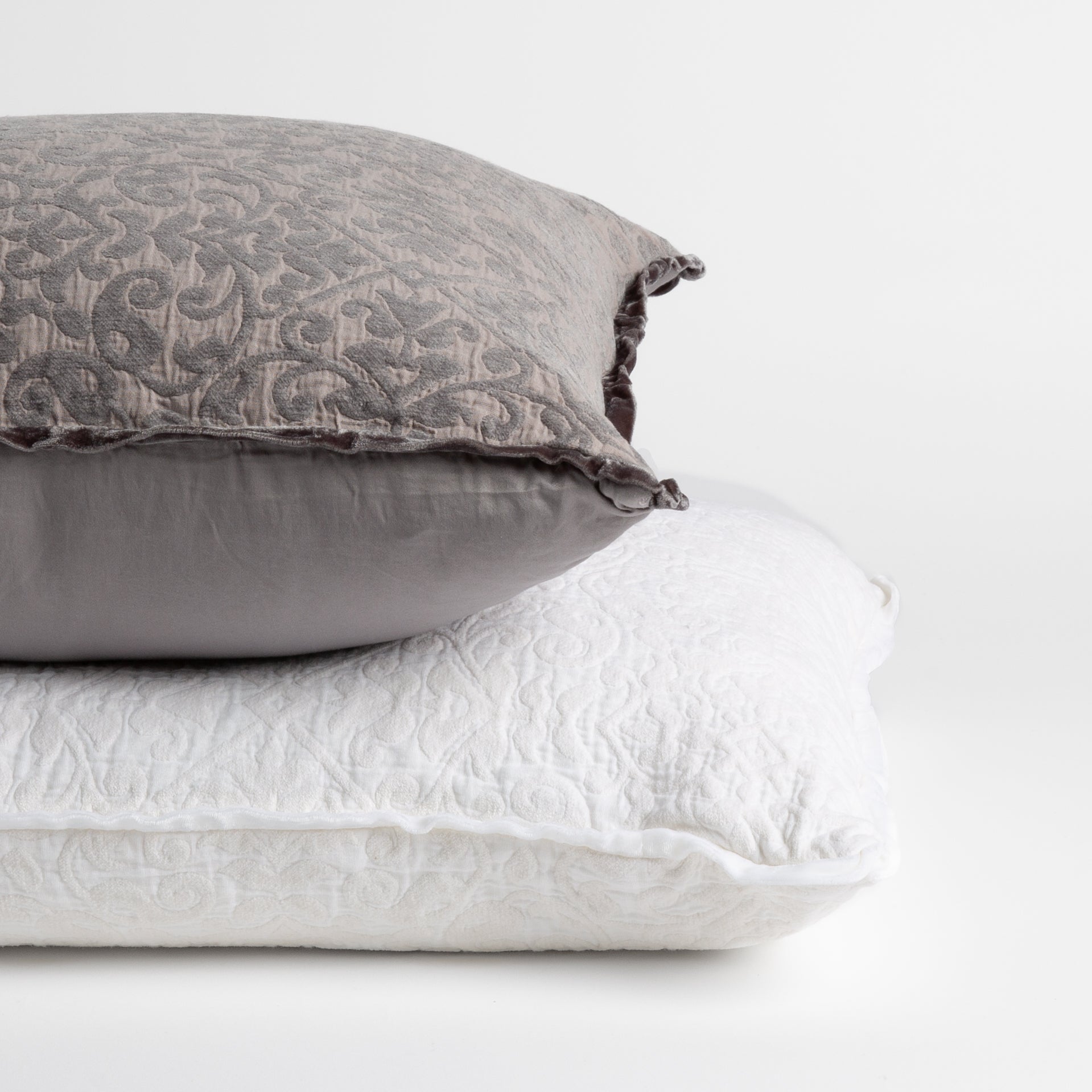 : two chenile jacquard pillows stacked to show different in their backing β straight on against a white background.
