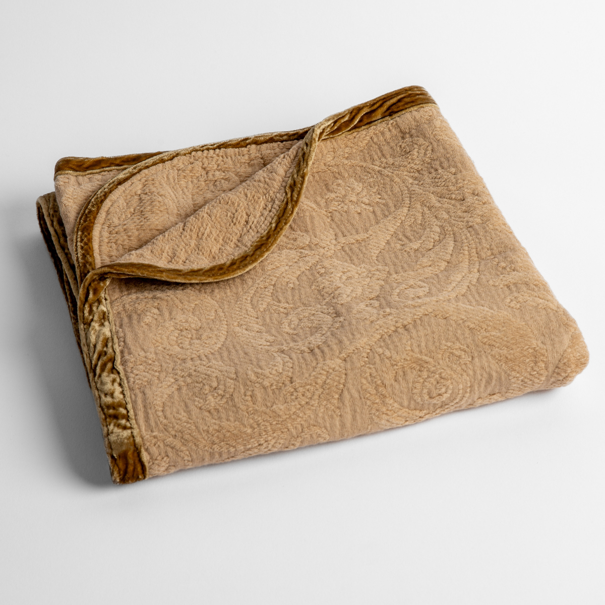 Honeycomb: a folded blanket with the corner turned down to show the trim against a white background, shot from an overhead angle. 