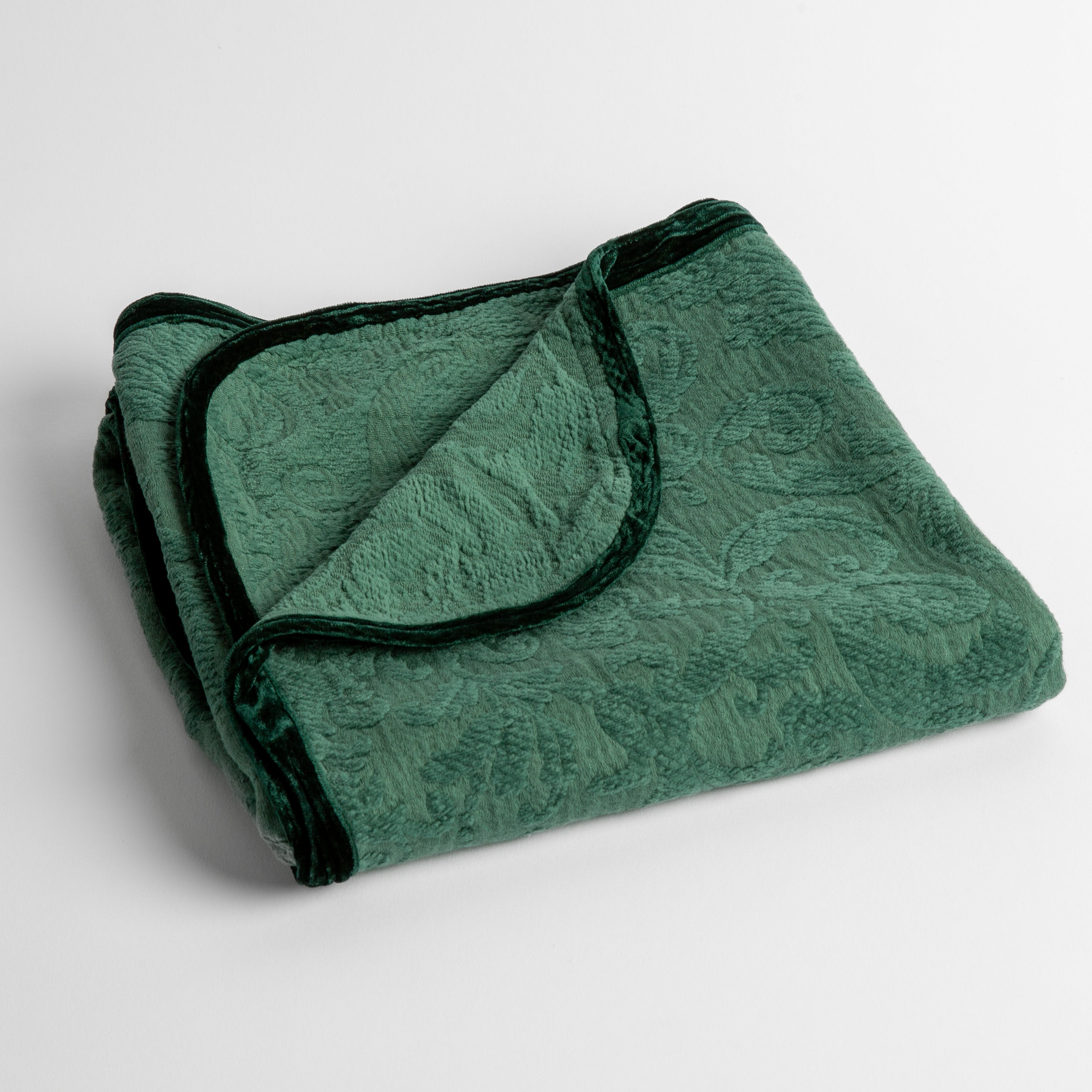An organic cotton damask baby blanket with silk velvet trim shown in jade, a vibrant green. 