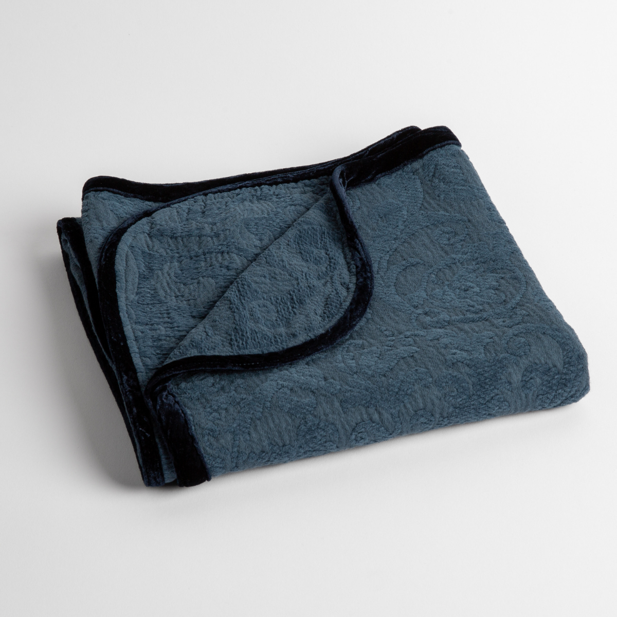 Midnight:  White: a folded blanket with the corner turned down to show the trim against a white background, shot from an overhead angle. 