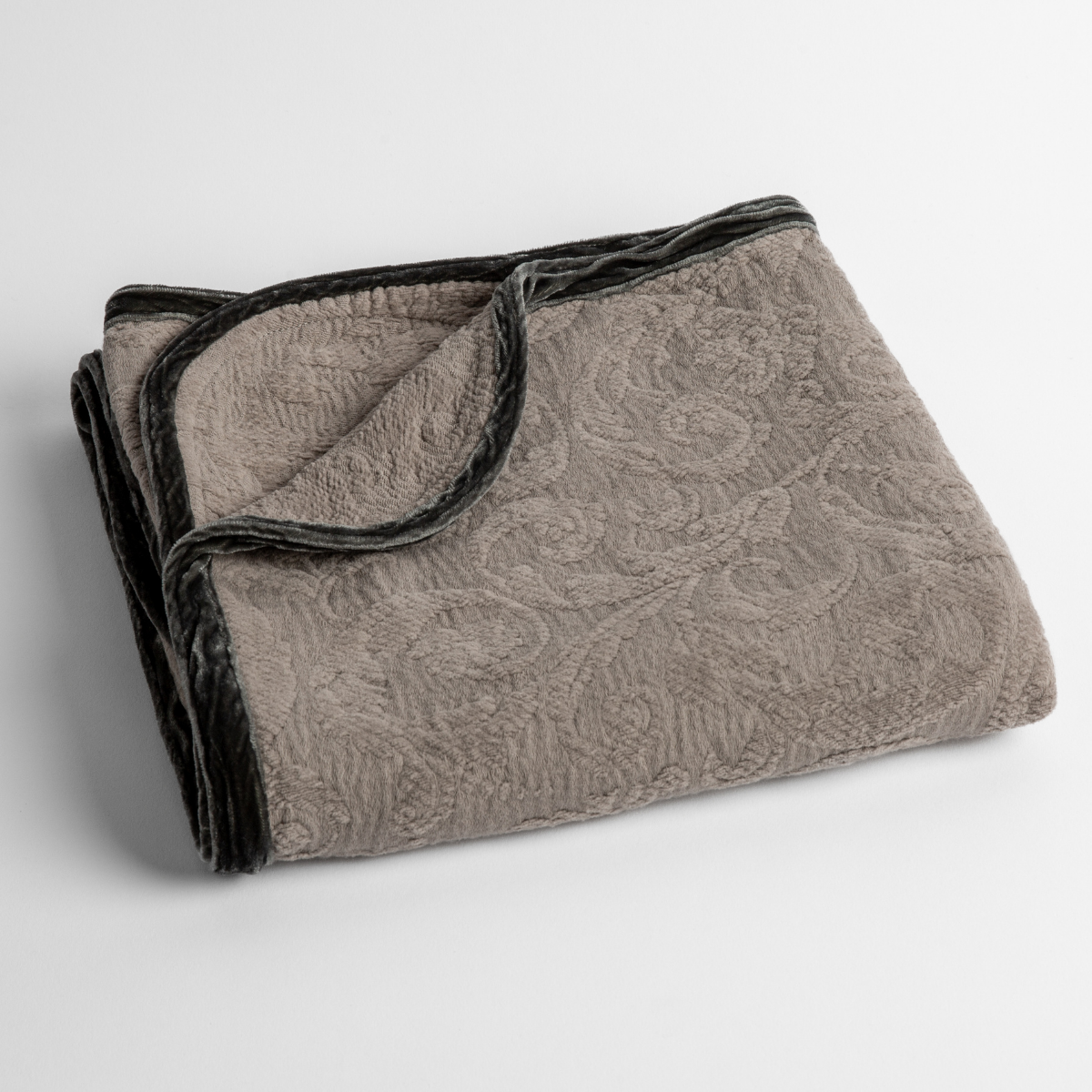 Moonlight: a folded blanket with the corner turned down to show the trim against a white background, shot from an overhead angle. 