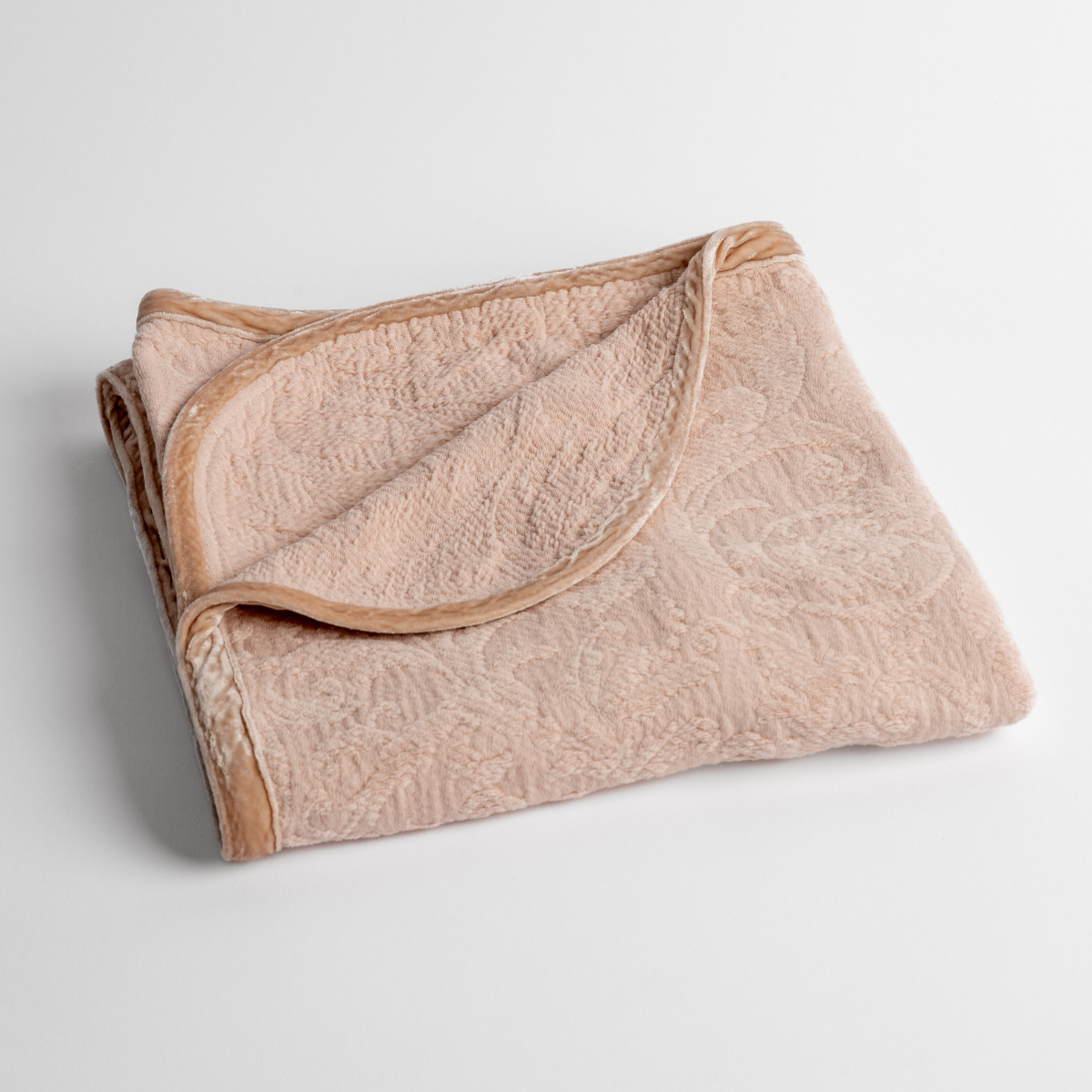 Pearl:  a folded blanket with the corner turned down to show the trim against a white background, shot from an overhead angle. 