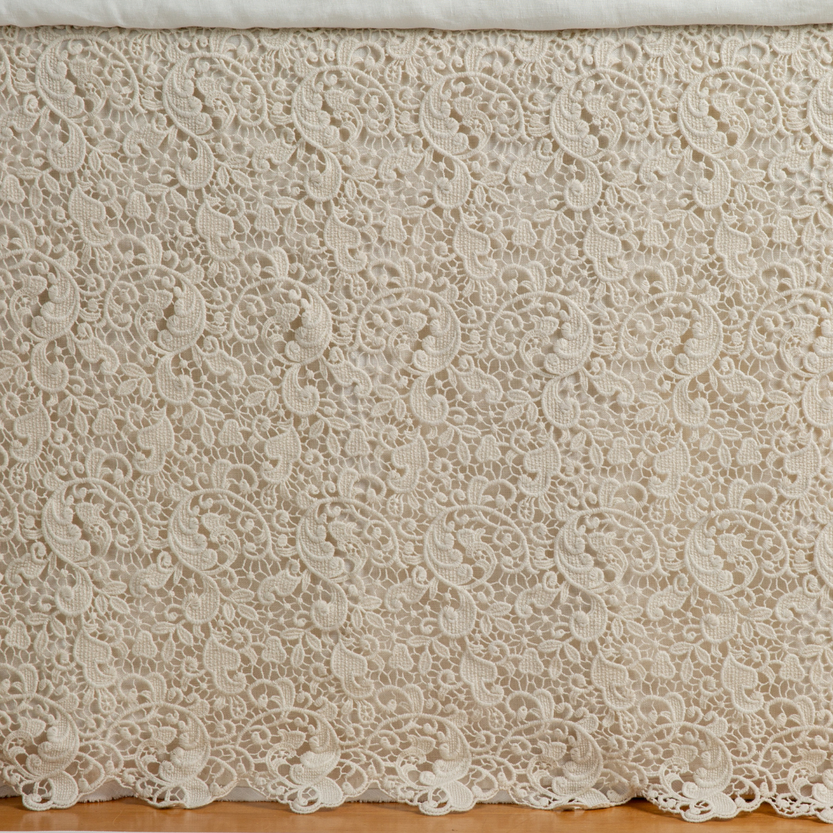 Parchment: a close up of a cotton lace bed skirt layered over a winter white bed skirt - shot straight at the bed skirt. 