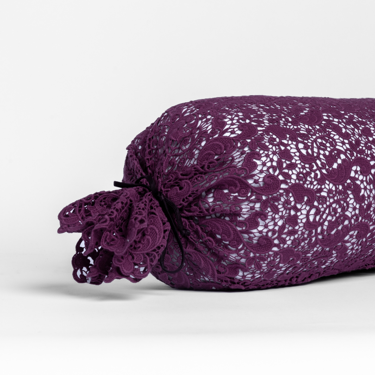 Fig: one end of a lace boslter cover on a winter white liner against a white background. 